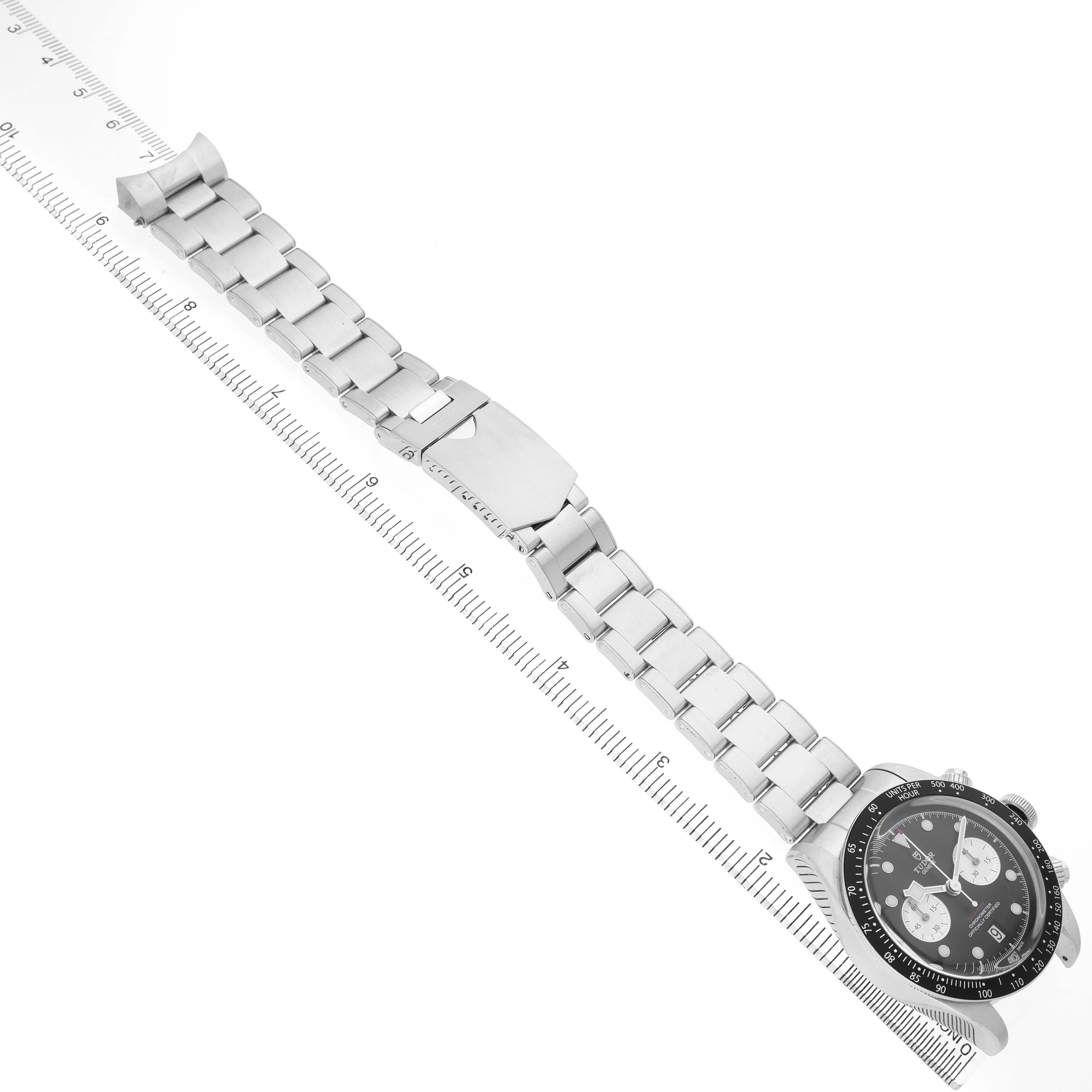 The image shows a Tudor Heritage Chrono 79360N-0001 Men's Stainless Steel Black Dial watch at an angled view, highlighting its bracelet and clasp alongside a measuring ruler.