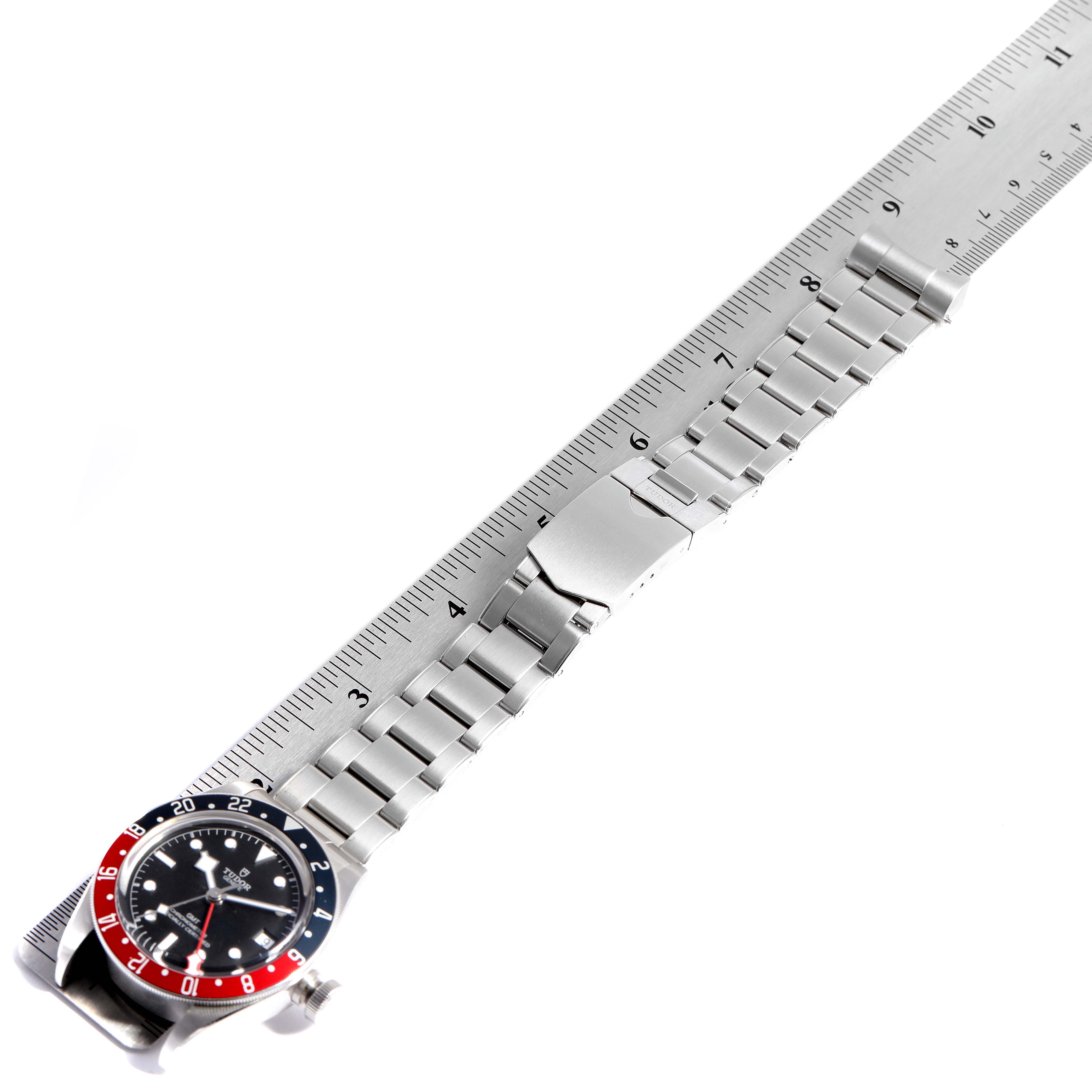 The image shows a Tudor Heritage Black Bay 79830RB Men
s Stainless Steel Black Dial 79830RB Men
s Stainless Steel Black Dial watch laid flat next to a ruler, displaying its full metal bracelet and clasp.