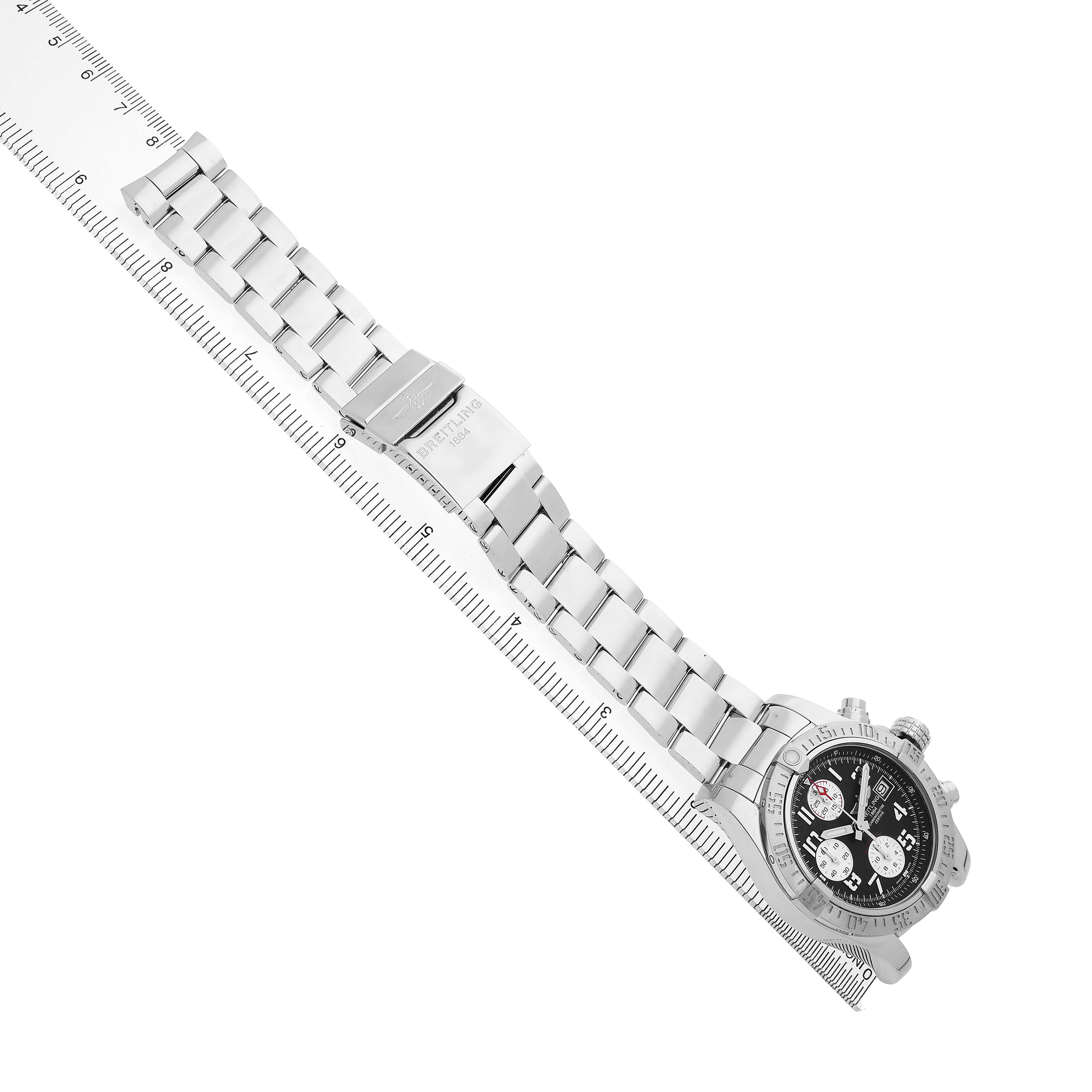 The Breitling Avenger A1338111 / F564 Men's Stainless Steel Black Dial watch is displayed at an angle showing the metallic bracelet and face, alongside a ruler for scale.