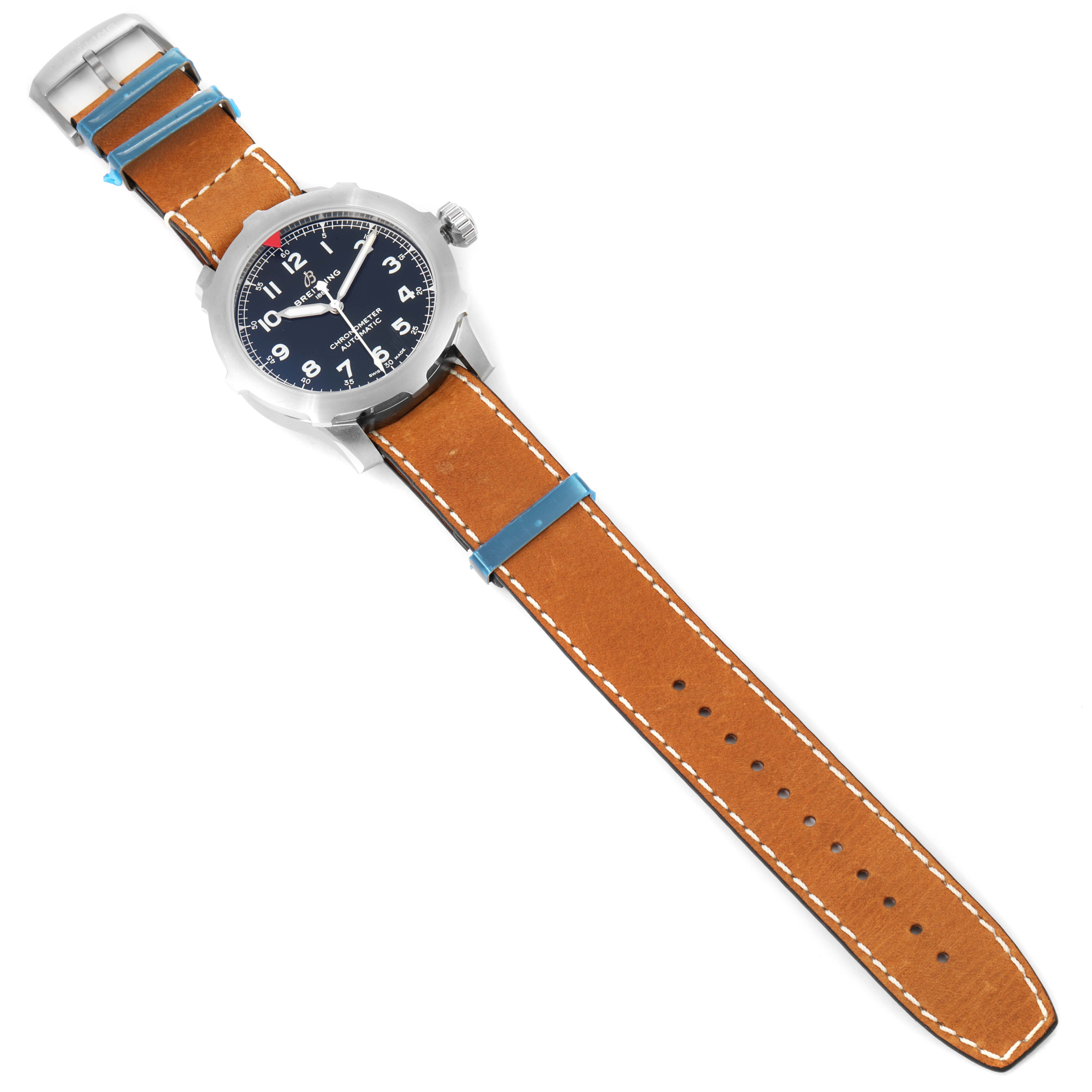 The image shows a top view of a Breitling Navitimer watch with a brown leather strap and a blue dial.