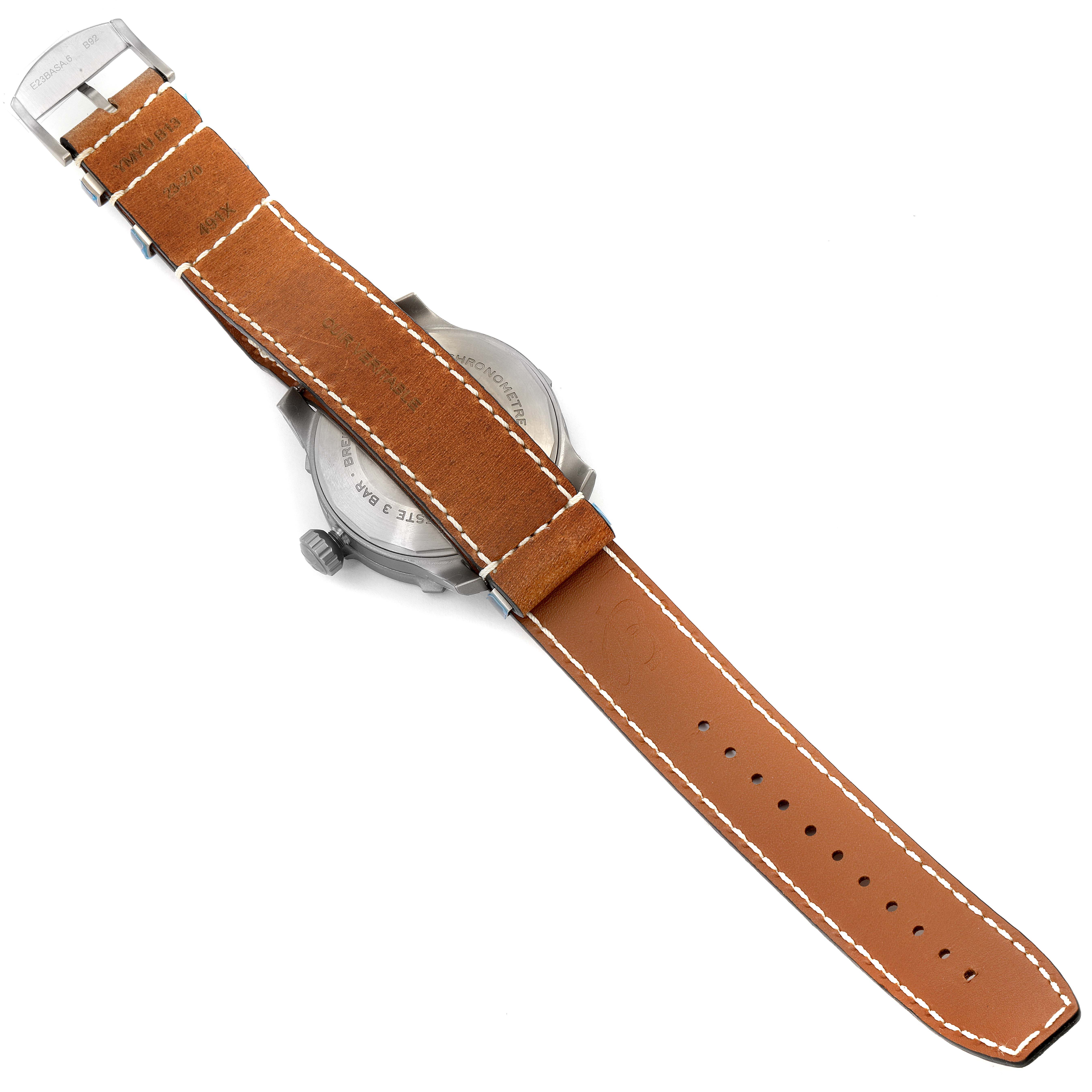 The image shows the back of a Breitling Navitimer watch with a brown leather strap and clasp.