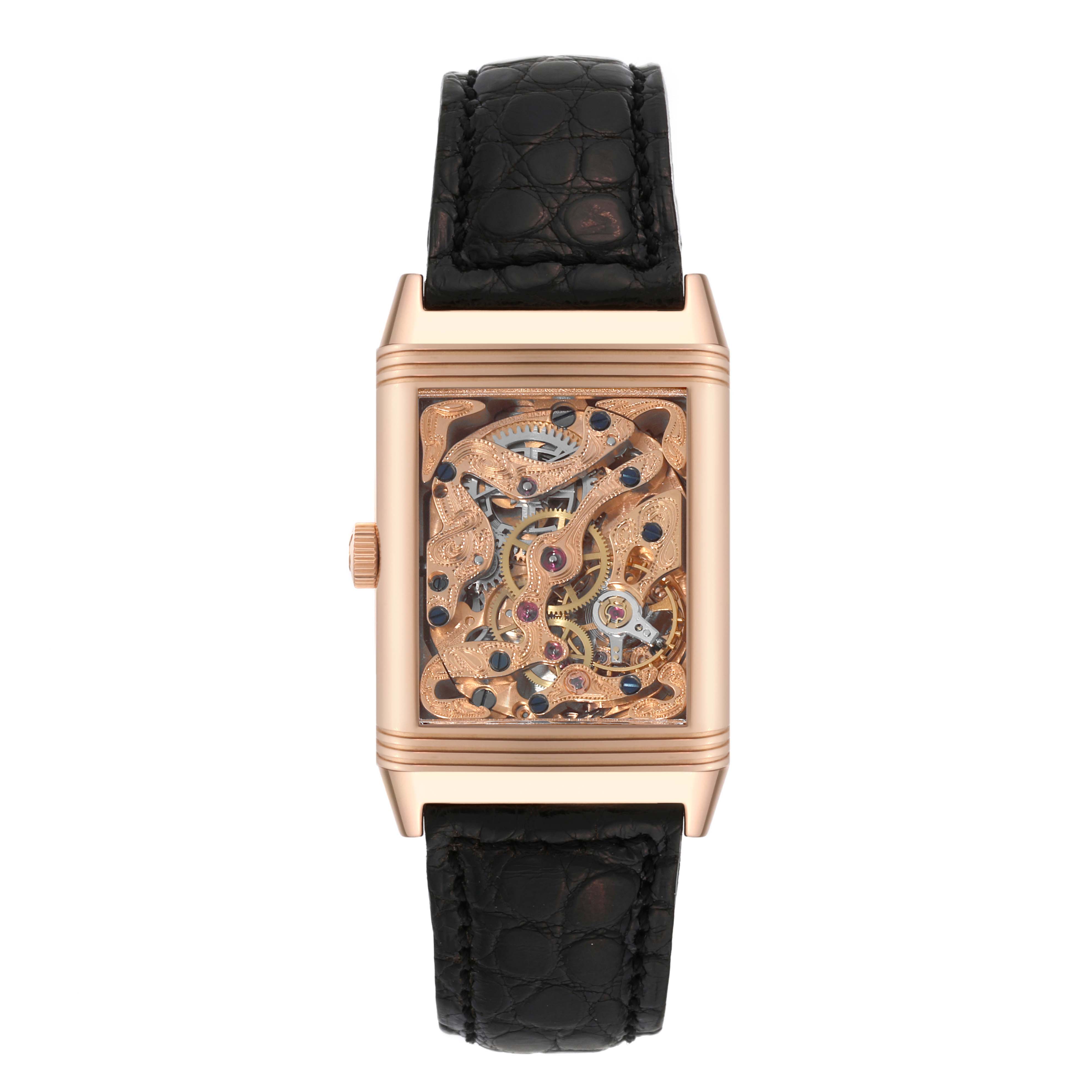 The image shows a Jaeger-LeCoultre Reverso watch in a front view, highlighting its intricate open-work dial and black leather strap.