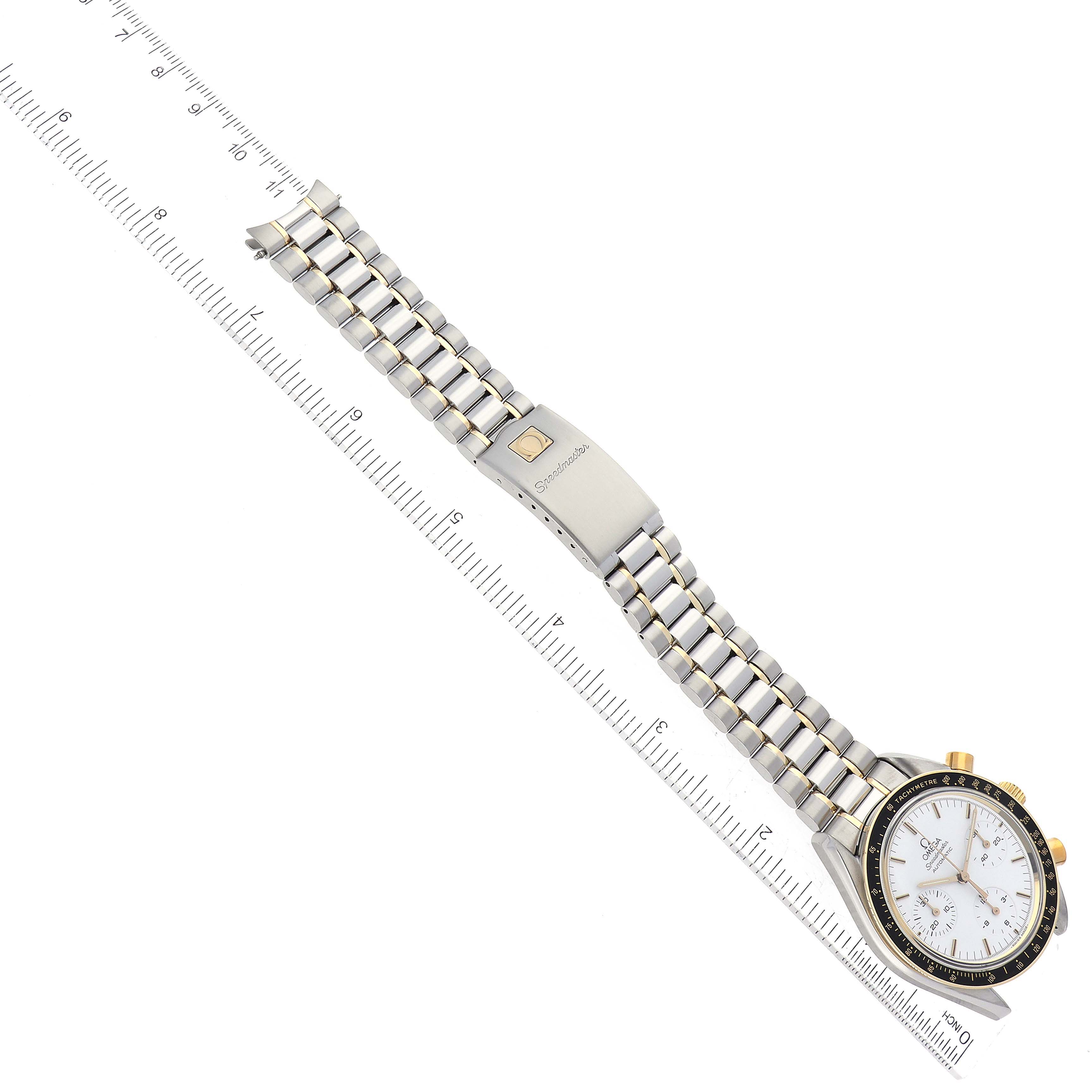 The image shows an overhead view of the Omega Speedmaster 3310.20.00 Men's Steel and Gold (two tone) White Dial 3310.20.00 Men's Steel and Gold (two tone) White Dial watch with the face and full-length bracelet visible alongside a ruler for scale.
