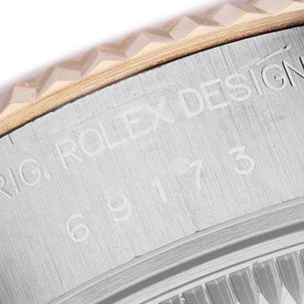 The image shows a close-up of the case edge with engraving and part of the fluted bezel on a Rolex Datejust 69173 Women's Steel and Gold (two tone) White Dial.