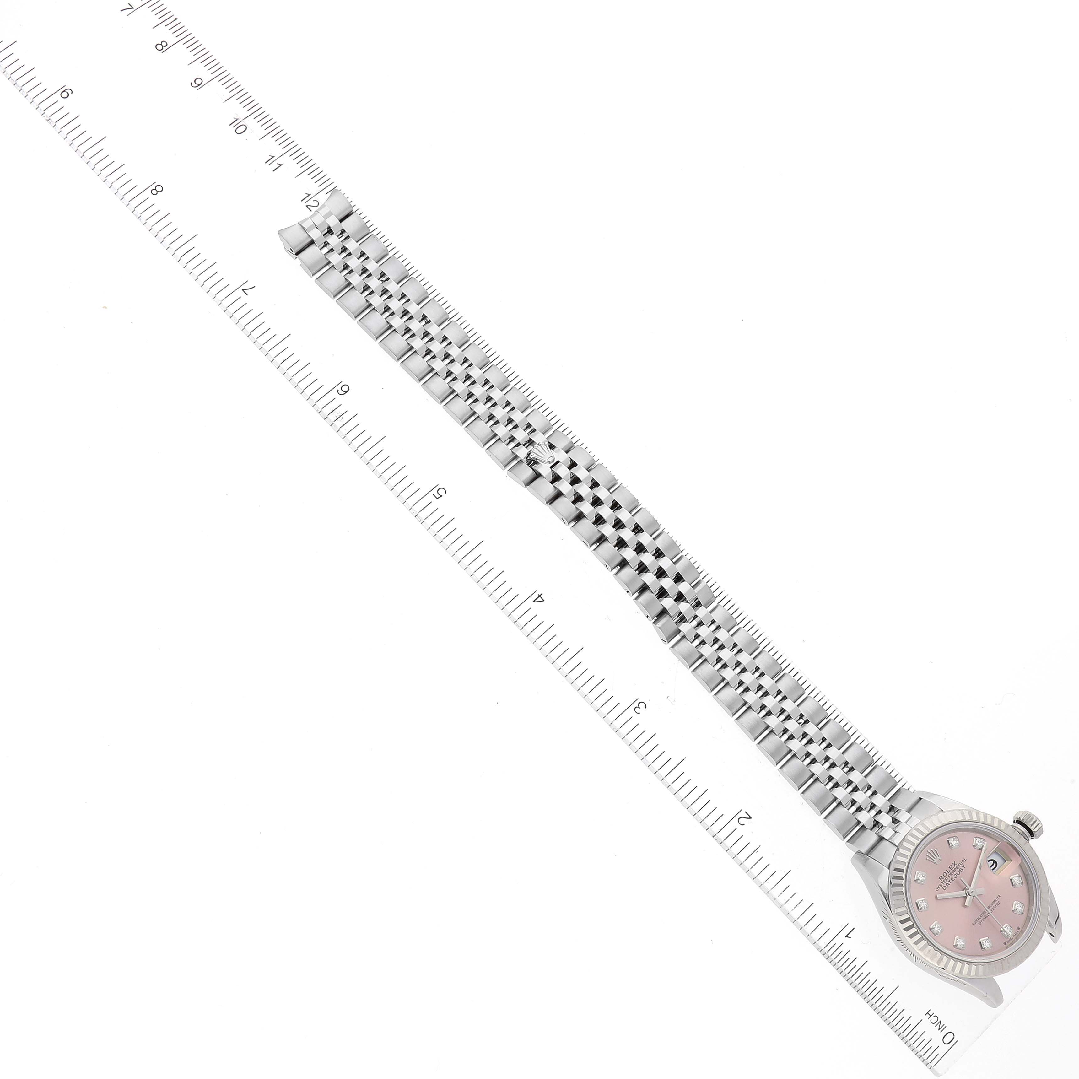 The image shows a top-down view of a Rolex Datejust 279174 Women's Stainless Steel Pink Dial 279174 Women's Stainless Steel Pink Dial watch, displaying its face, bracelet, and two rulers for scale.