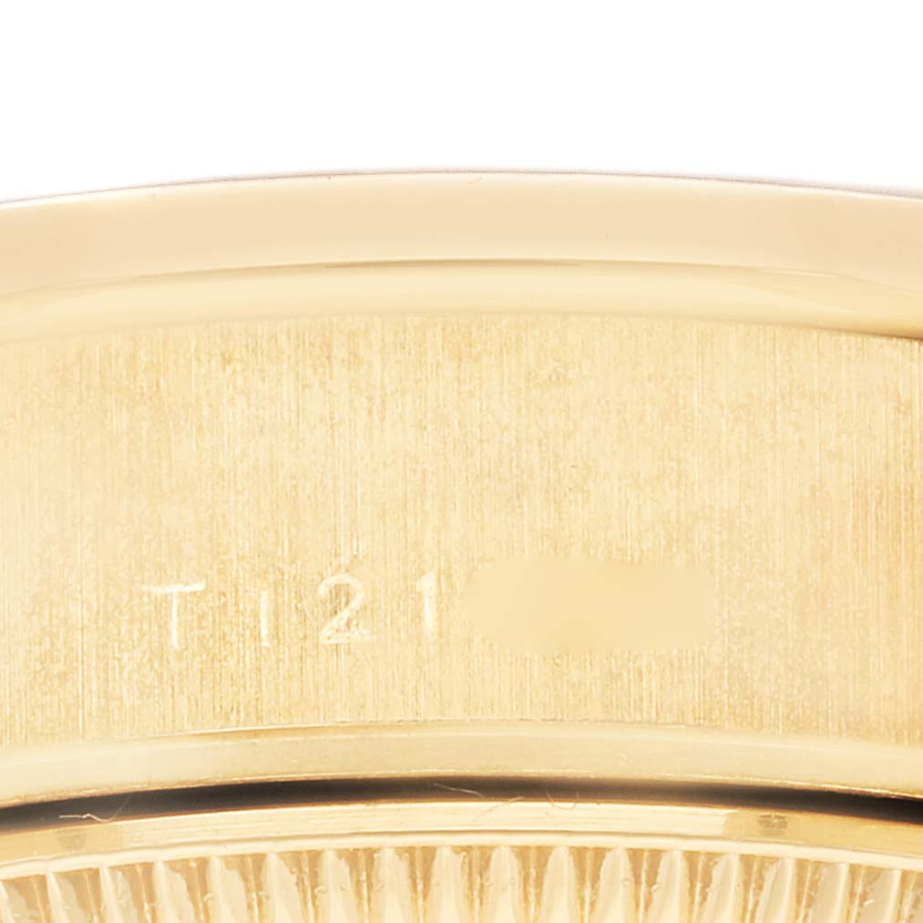 The image shows a close-up of the Rolex President 69138 Women's Yellow Gold Black Dial 69138 Women's Yellow Gold Black Dial model's gold case with part of the serial number visible.