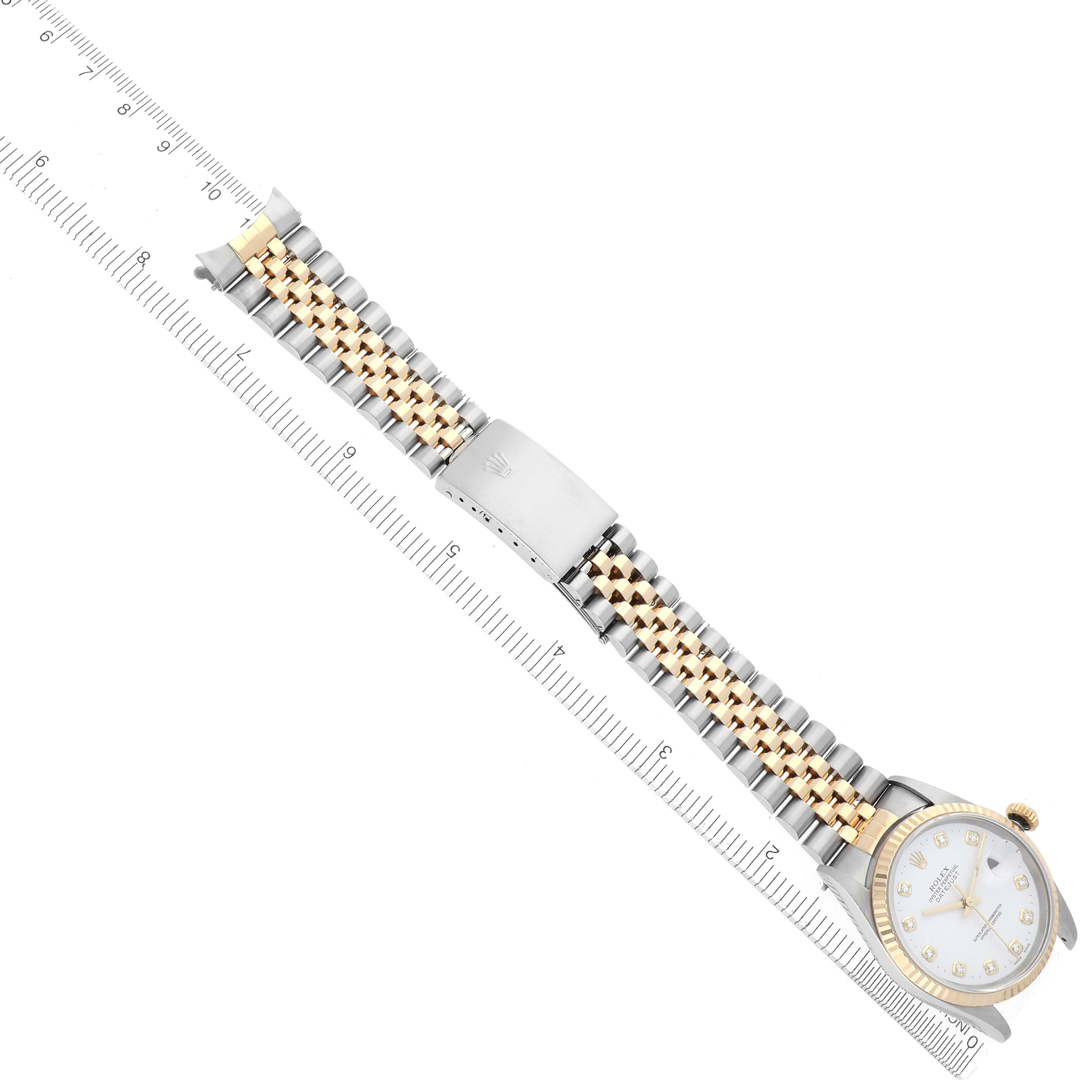 The Rolex Datejust 16233 Men's Steel and Gold (two tone) White Dial 16233 Men's Steel and Gold (two tone) White Dial is shown from an overhead angle, highlighting the bracelet, clasp, and face alongside a measuring ruler.