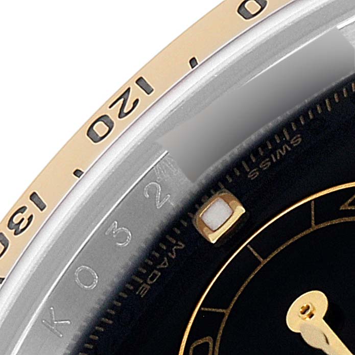 This image shows a close-up of the bezel and part of the dial of a Rolex Daytona 116523 Men
s Steel and Gold (two tone) Black Dial 116523 Men
s Steel and Gold (two tone) Black Dial watch.