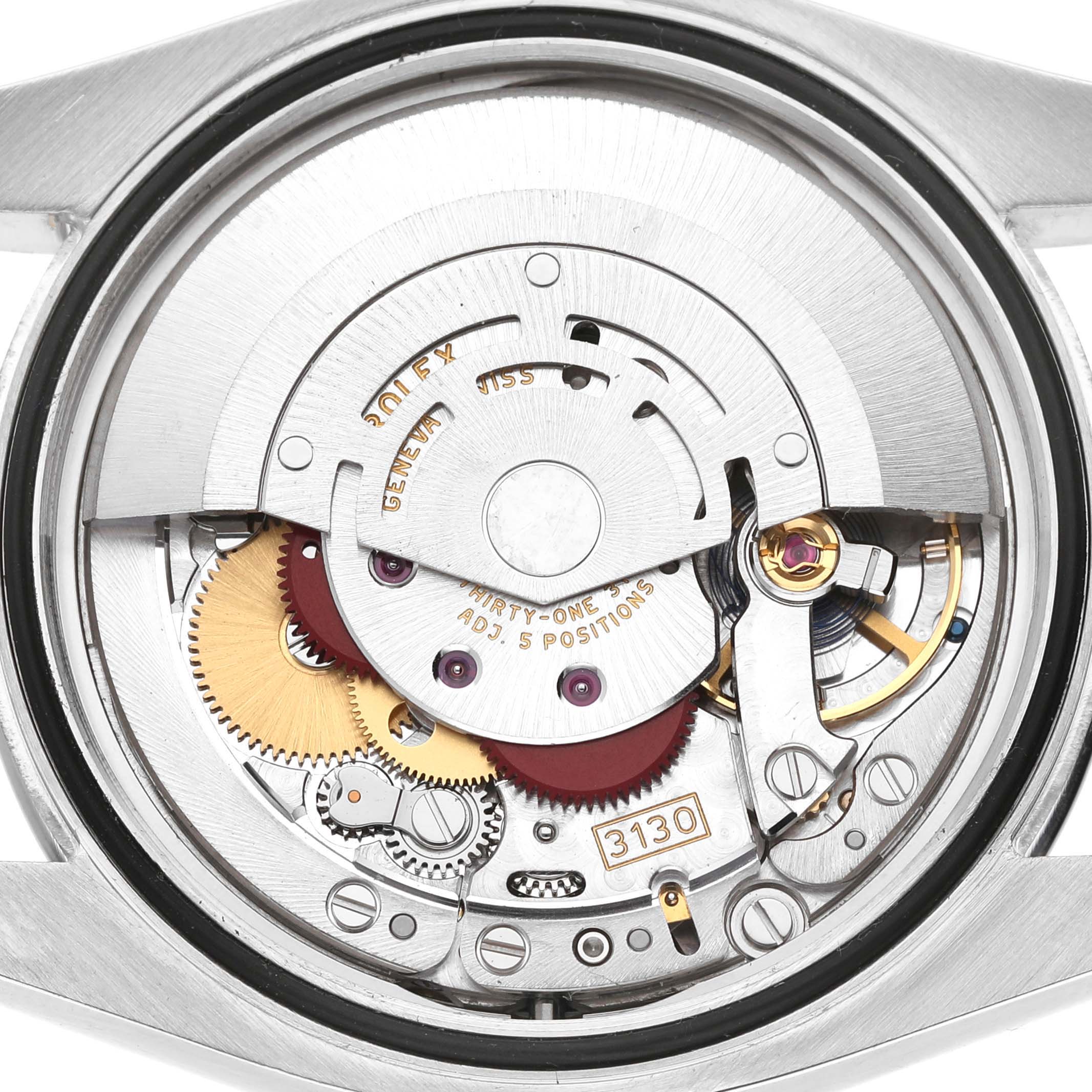The image shows the internal movement of a Rolex Oyster Perpetual 116000 Men's Stainless Steel Blue Dial watch, viewed from the back, displaying its intricate gears and rotor.