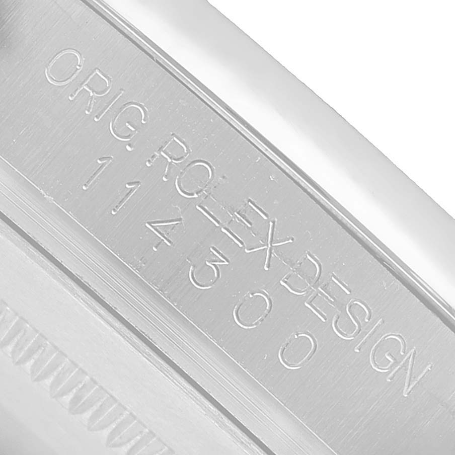 This image shows a close-up of the engraved case side of a Rolex Oyster Perpetual 114300 Men's Stainless Steel Blue Dial watch, highlighting the model number.