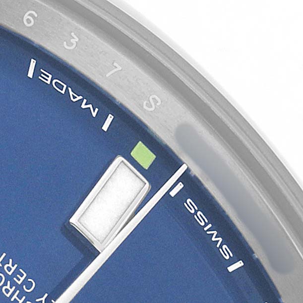 The image shows a close-up of the Rolex Oyster Perpetual 114300 Men's Stainless Steel Blue Dial dial with hour markers and the words "SWISS MADE."