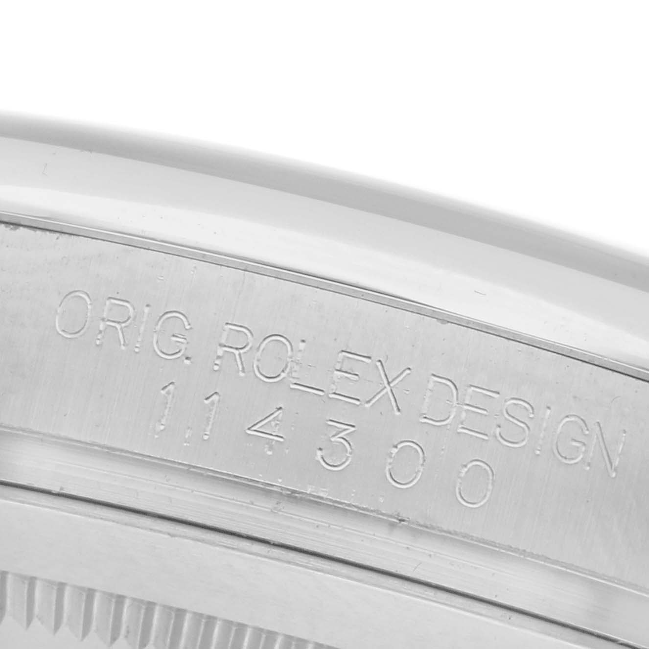 The image shows a close-up of the inner bezel engravings on a Rolex Oyster Perpetual 114300 Men's Stainless Steel Grey Dial 114300 Men's Stainless Steel Grey Dial watch, featuring the model number.