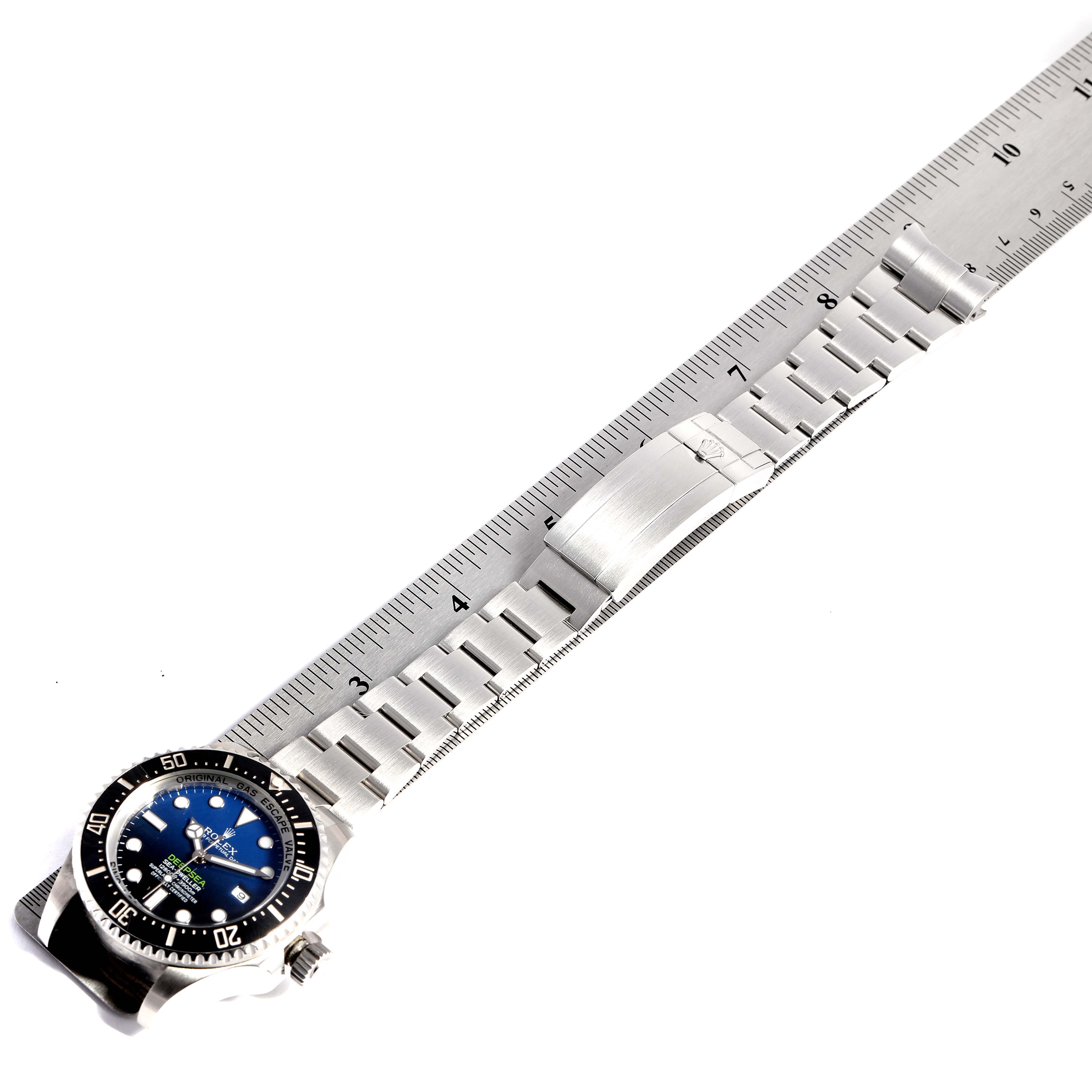The image shows a top-down view of a Rolex Sea-Dweller 116660 Men's Stainless Steel Blue Dial 116660 Men's Stainless Steel Blue Dial watch with a full view of its metal bracelet placed alongside a ruler.