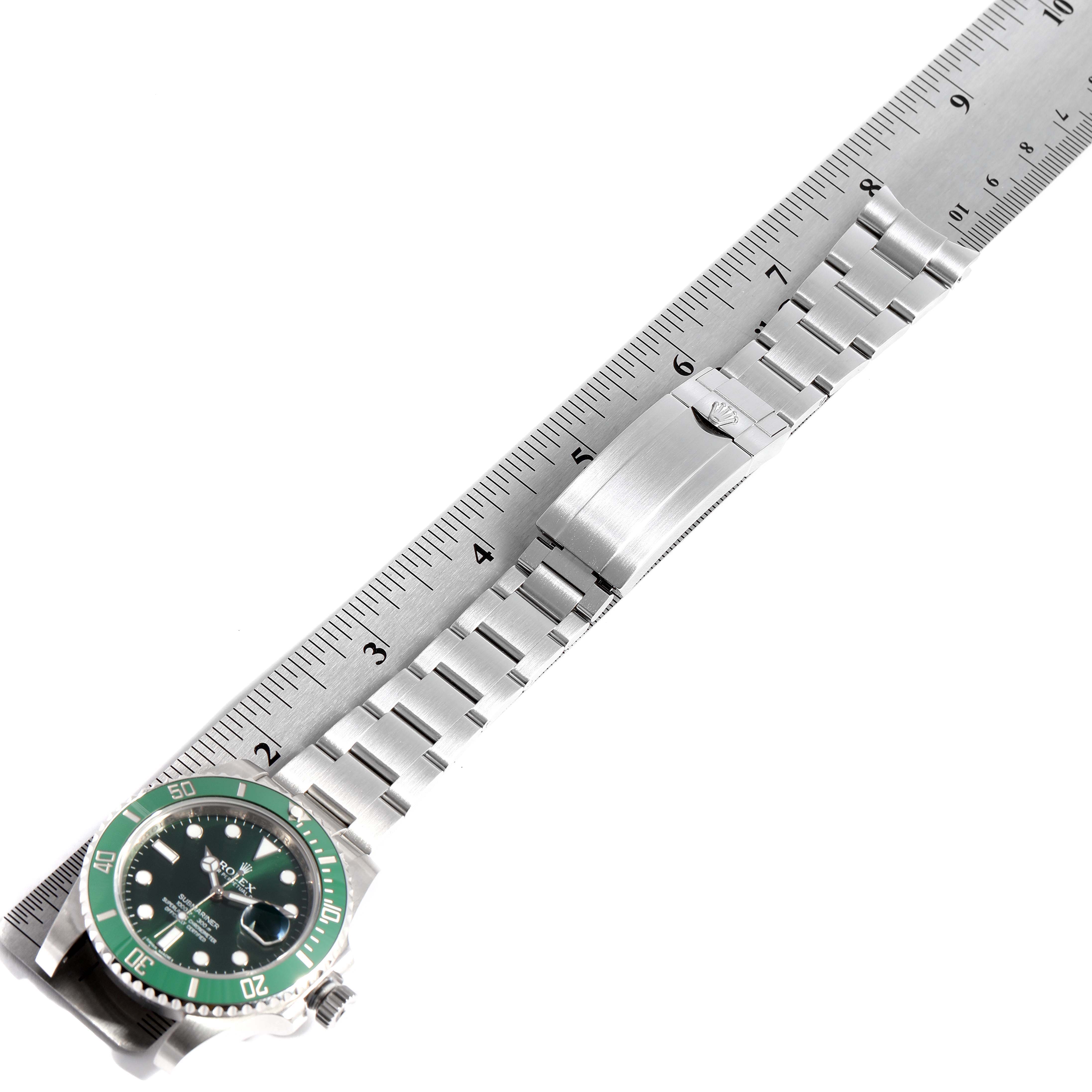 The image shows a Rolex Submariner 116610LV Men's Stainless Steel Green Dial 116610LV Men's Stainless Steel Green Dial watch laid flat beside a ruler, highlighting its bracelet and clasp.