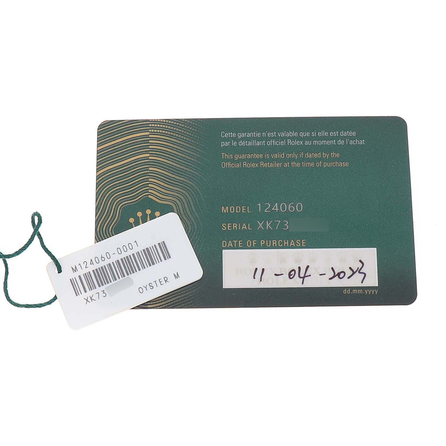 The image shows a Rolex Submariner M124060-0001 Men's Stainless Steel Black Dial model warranty card with model number 124060 and a tag displaying additional details.