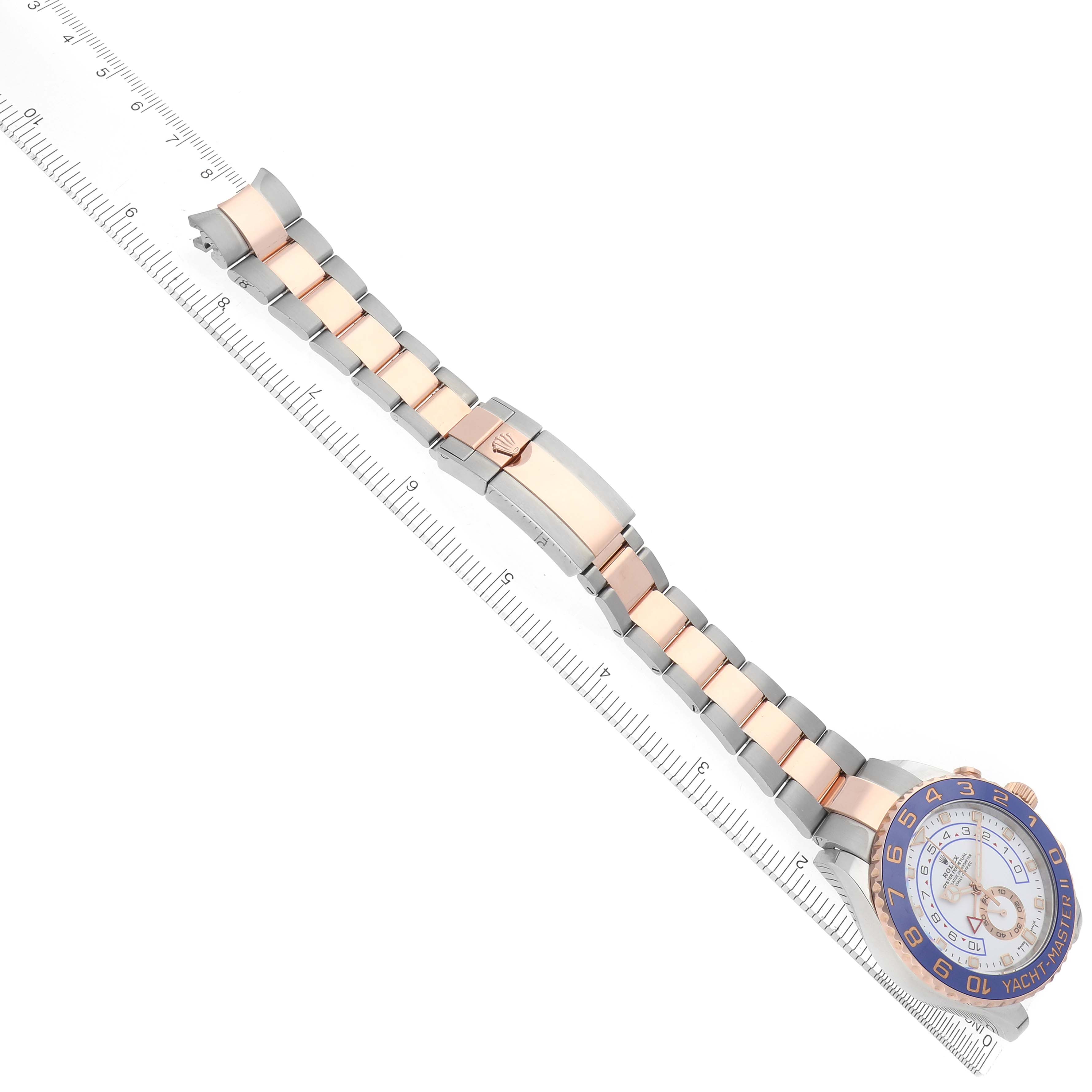 The Rolex Yacht-Master 116681 Men's Steel and Gold (two tone) White Dial 116681 Men's Steel and Gold (two tone) White Dial watch is displayed from a top-down angle, showing the face, bezel, and bracelet alongside a ruler.