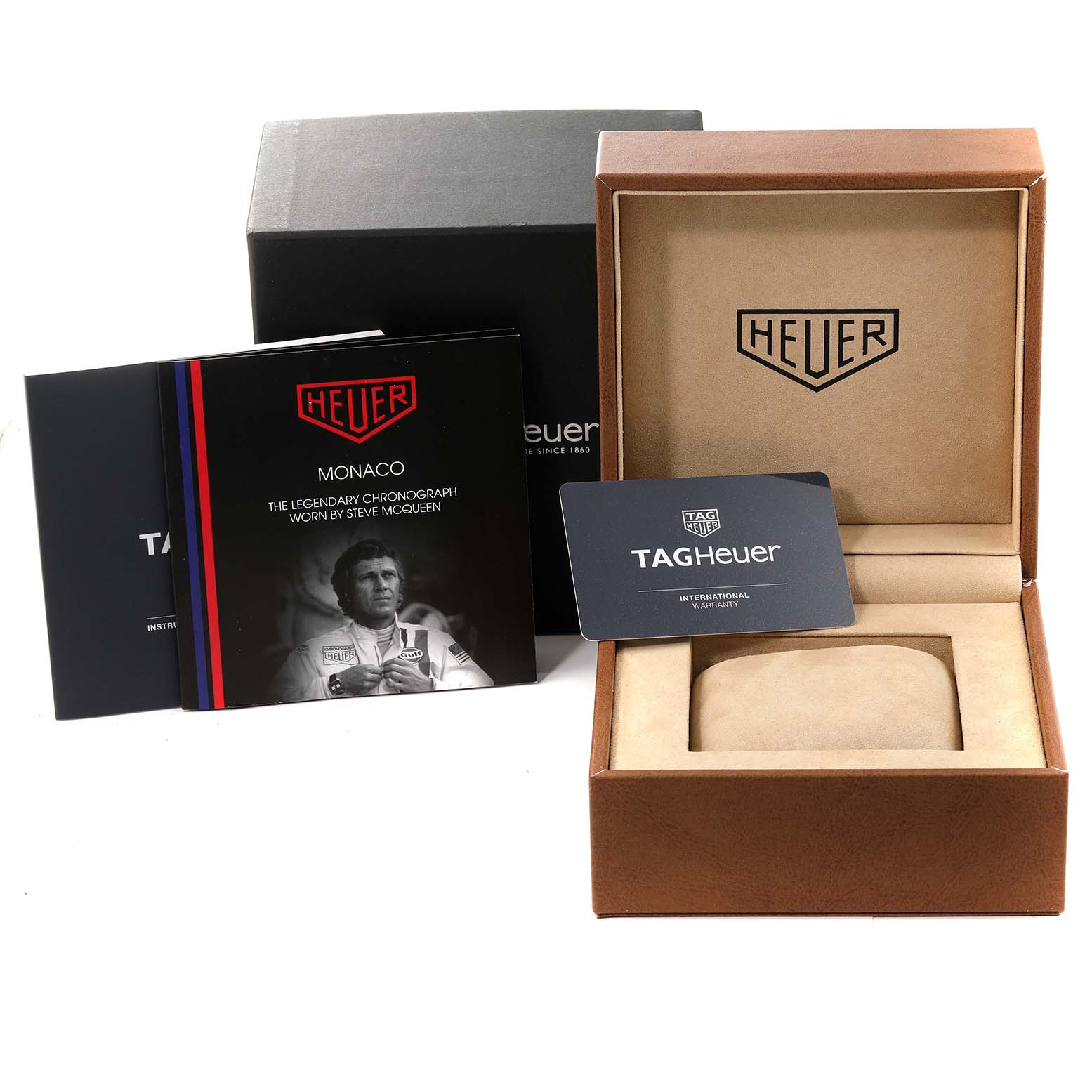 The image shows the packaging and accessories of the Tag Heuer Monaco CAW211P.FC6356 Men's Stainless Steel Blue Dial CAW211P.FC6356 Men's Stainless Steel Blue Dial watch, including the box, warranty card, and instruction manual.