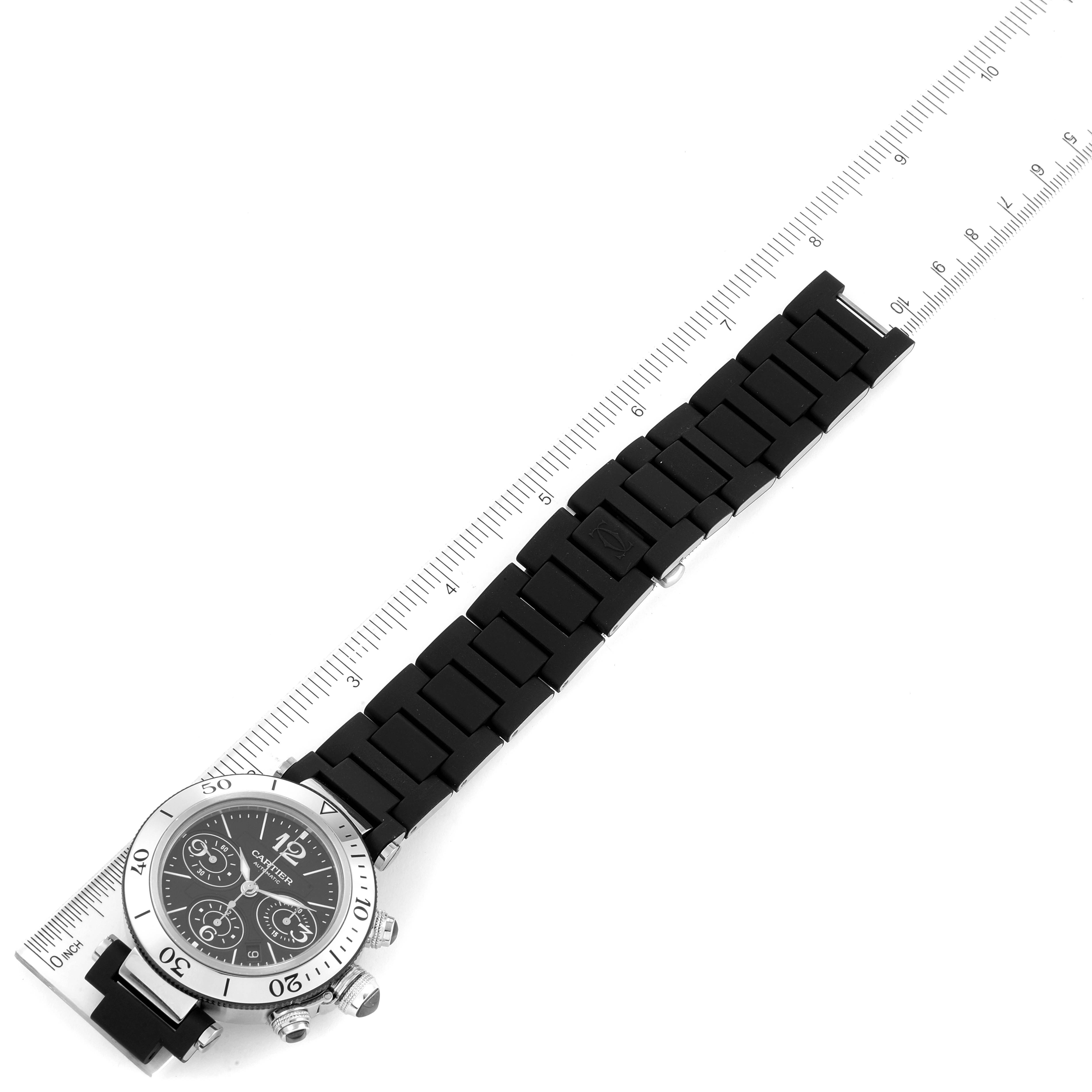 The Cartier Pasha W31088U2 Men
s Stainless Steel Black Dial W31088U2 Men
s Stainless Steel Black Dial watch is shown from a top-down angle with its entire face and black strap visible, placed alongside a ruler.