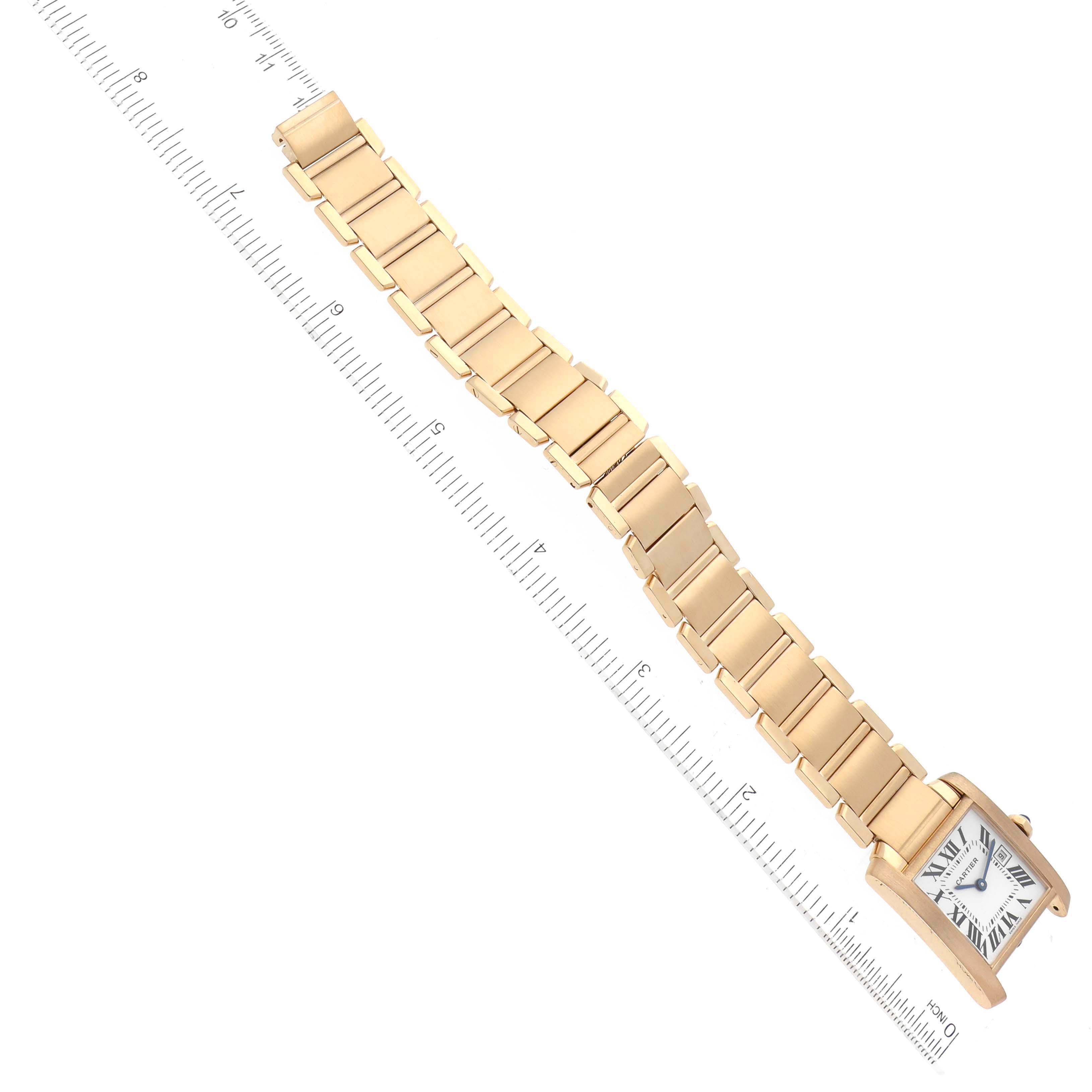 The image shows a Cartier Tank Française watch angled diagonally, displaying its face and full length of its gold bracelet against a ruler.