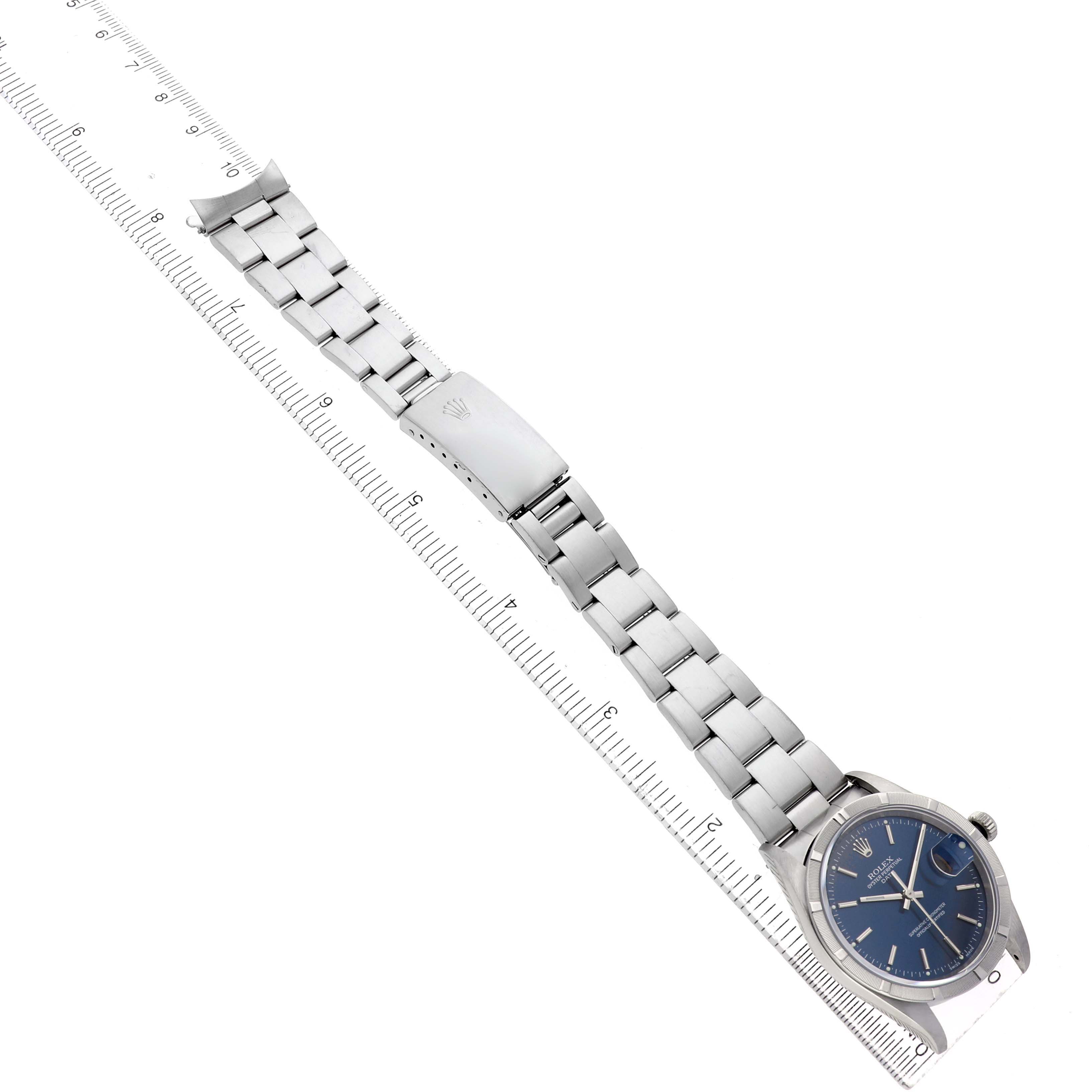The Rolex Date 15210 Men's Stainless Steel Blue Dial model watch is shown at an angle displaying the face, bezel, and full bracelet with a ruler for scale.