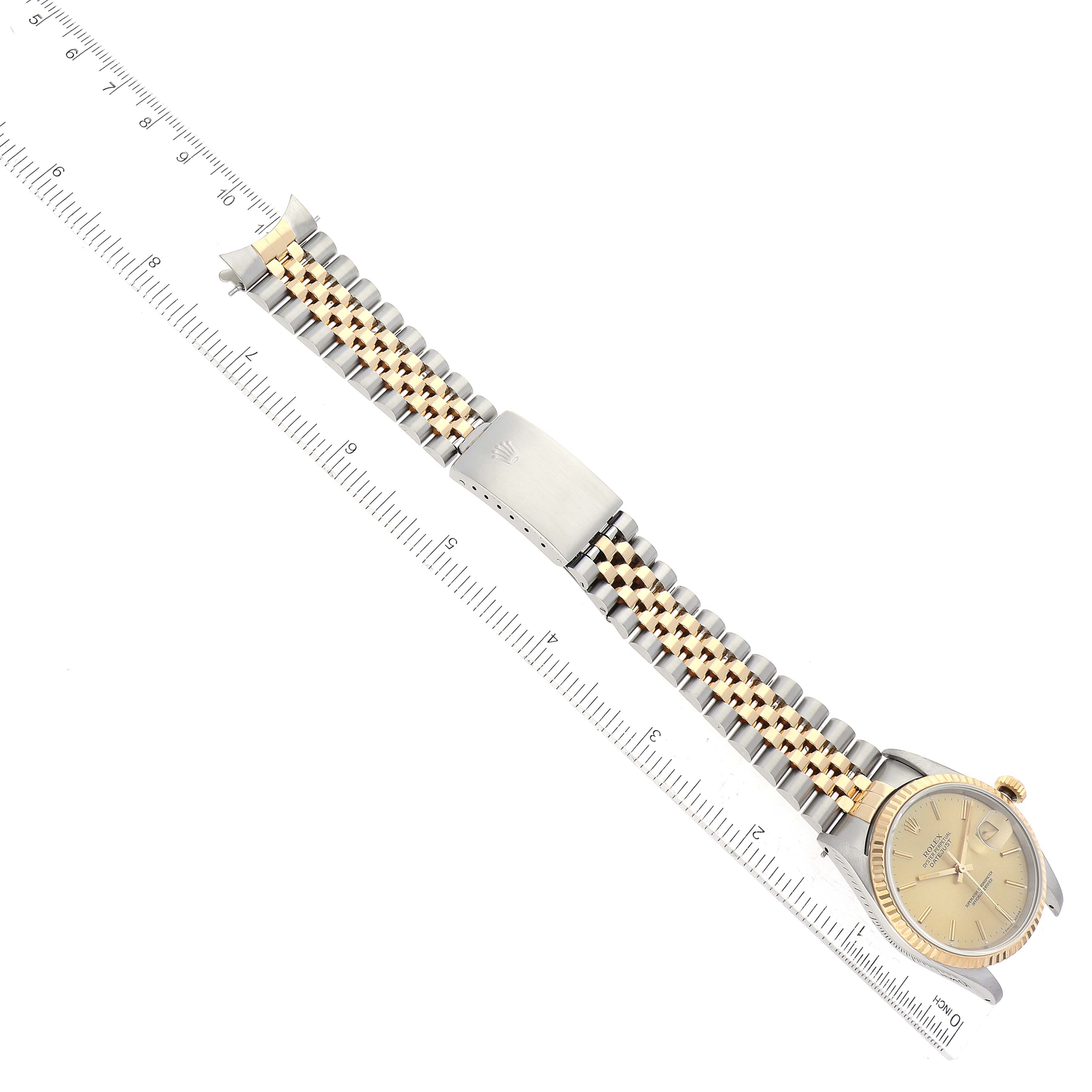 This image shows a Rolex Datejust 16233 Men's Steel and Gold (two tone) Champagne Dial 16233 Men's Steel and Gold (two tone) Champagne Dial watch laid flat with the dial and two-toned bracelet visible, alongside a ruler for scale.