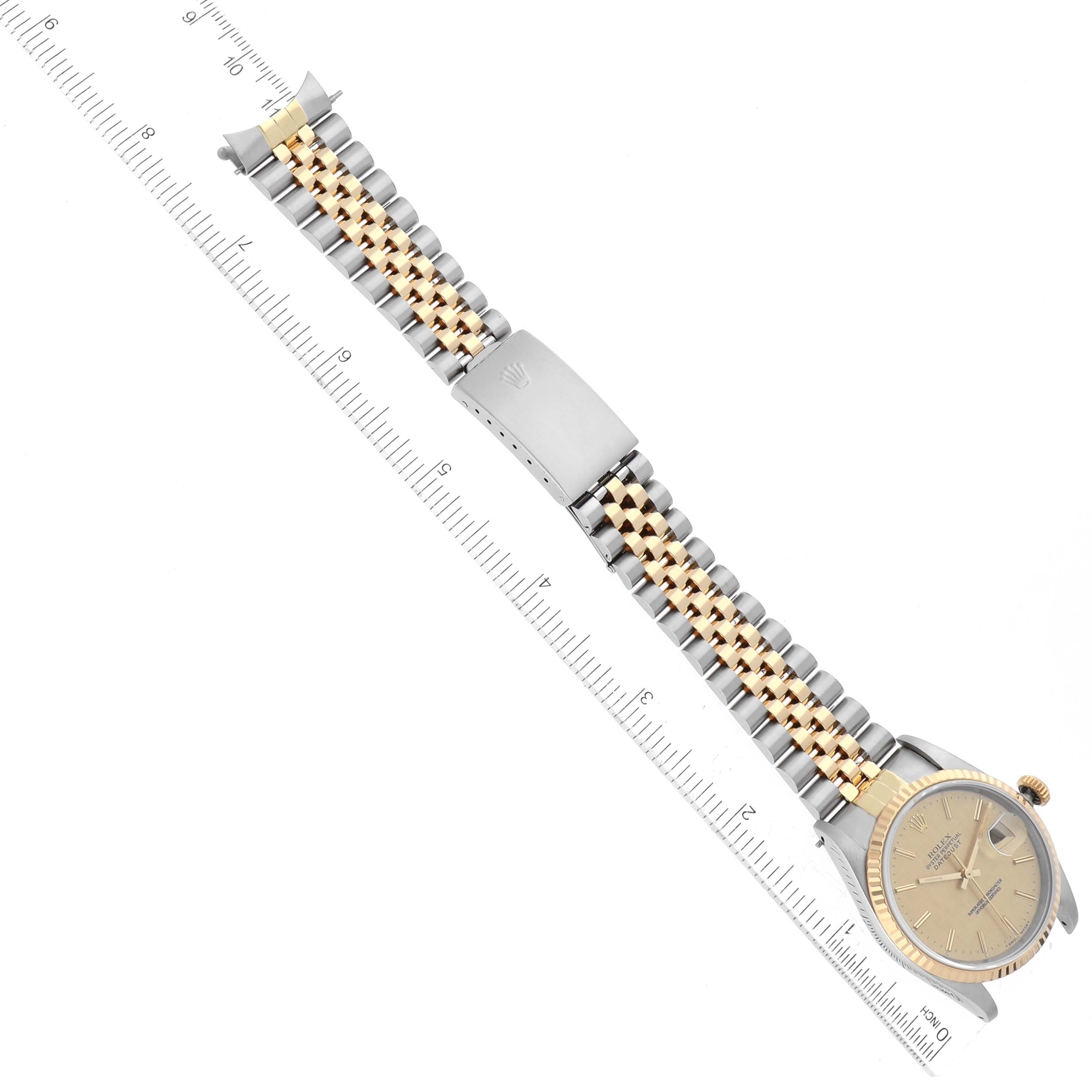 The image shows a Rolex Datejust 16233 Men's Steel and Gold (two tone) Champagne Dial 16233 Men's Steel and Gold (two tone) Champagne Dial watch laid flat with its gold and silver bracelet and clasp visible, along with a ruler for scale.