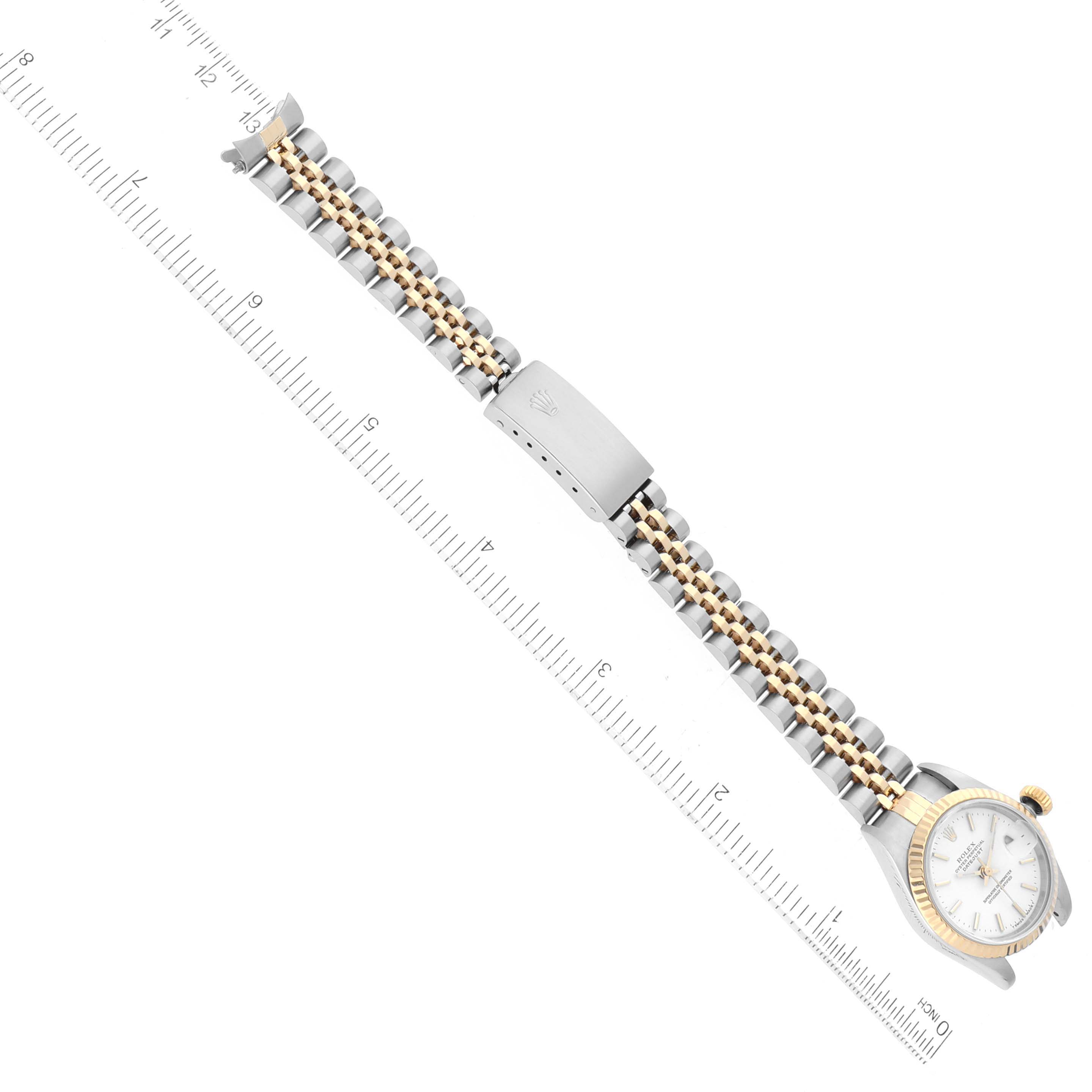 This image shows a Rolex Datejust 69173 Women's Steel and Gold (two tone) White Dial 69173 Women's Steel and Gold (two tone) White Dial watch with a two-tone band angled diagonally next to a ruler for size reference.