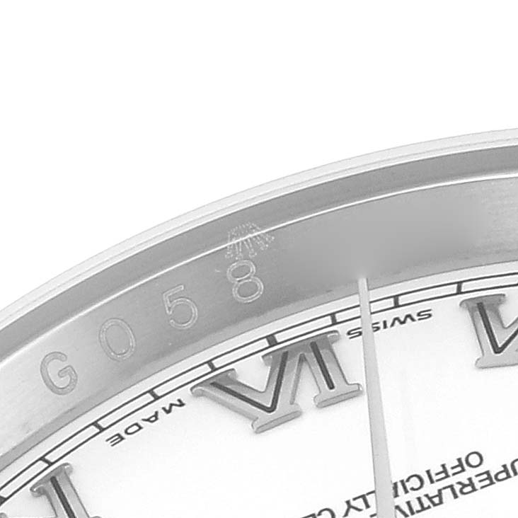 The image shows a close-up angle of a Rolex Datejust 116200 Men's Stainless Steel White Dial 116200 Men's Stainless Steel White Dial watch, focusing on the bezel with engraved numbers and part of the dial with Roman numerals.