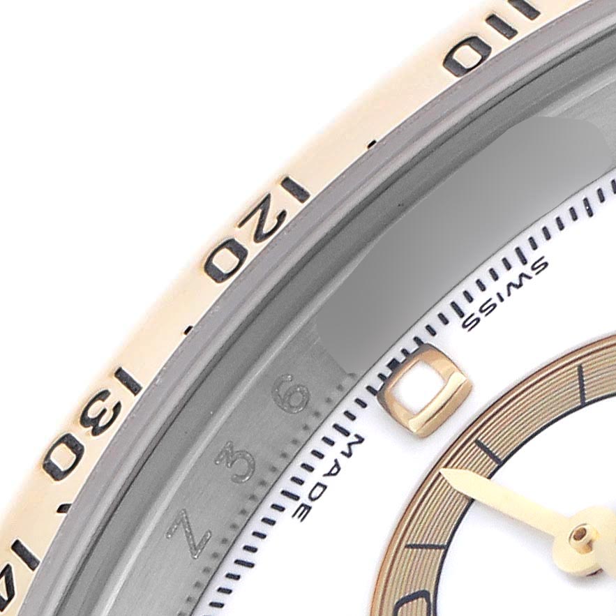 The image shows a close-up of the bezel and dial of a Rolex Daytona 116523 Men's Steel and Gold (two tone) White Dial 116523 Men's Steel and Gold (two tone) White Dial watch, highlighting the tachymetric scale and part of the hands.
