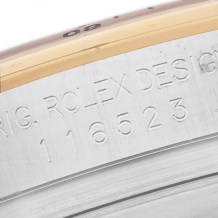 The image shows a close-up of the side engraving on the bezel of a Rolex Daytona 116523 Men's Steel and Gold (two tone) White Dial 116523 Men's Steel and Gold (two tone) White Dial watch, highlighting the model number and design details.