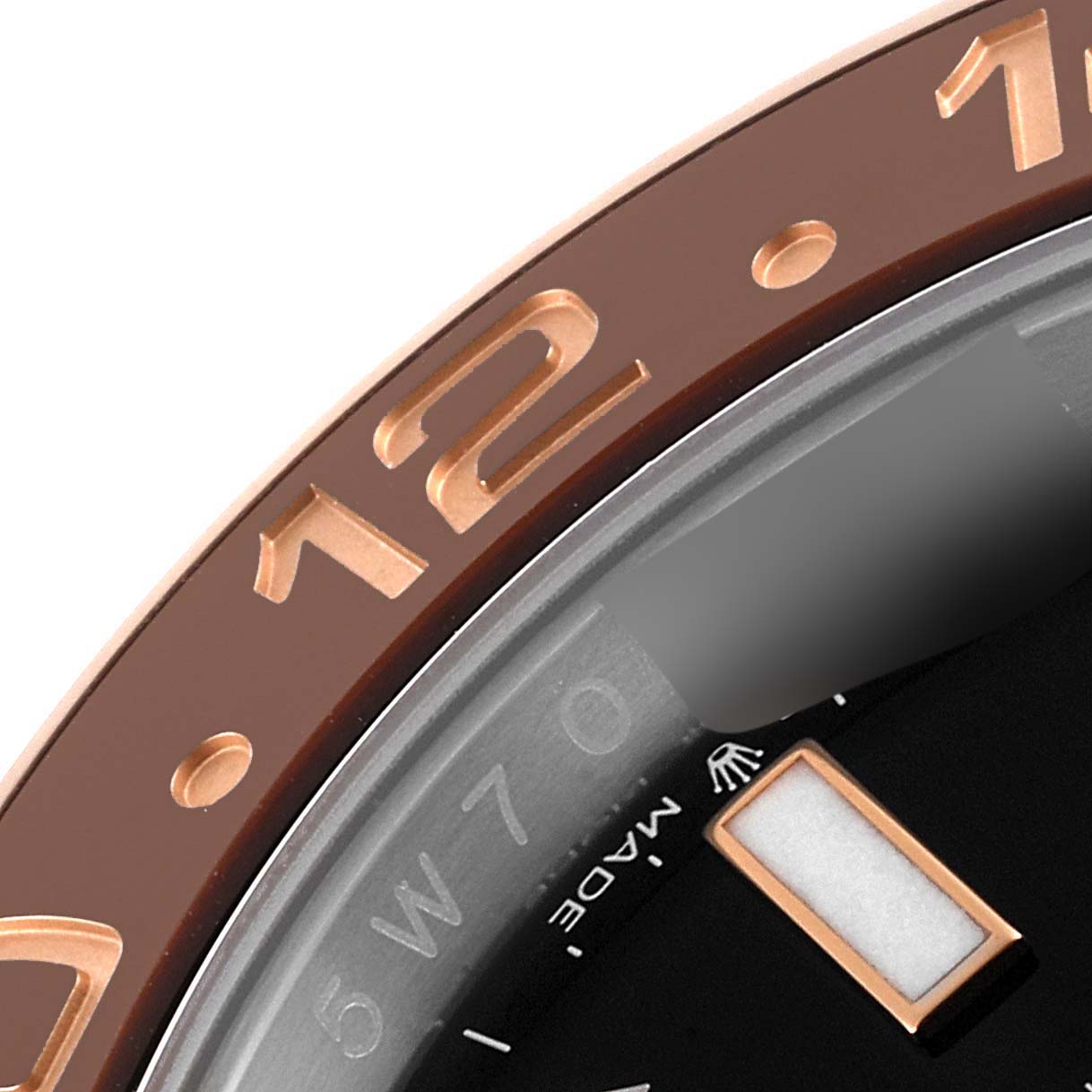 This close-up image of a Rolex GMT-Master 126711CHNR Men's Steel and Gold (two tone) Black Dial 126711CHNR Men's Steel and Gold (two tone) Black Dial watch shows part of the bezel and dial, including the "12" marker.