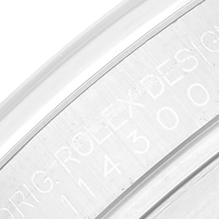 This image shows a close-up of the side of the bezel and case of a Rolex Oyster Perpetual 114300 Men
s Stainless Steel Grey Dial 114300 Men
s Stainless Steel Grey Dial watch, highlighting engraved text.