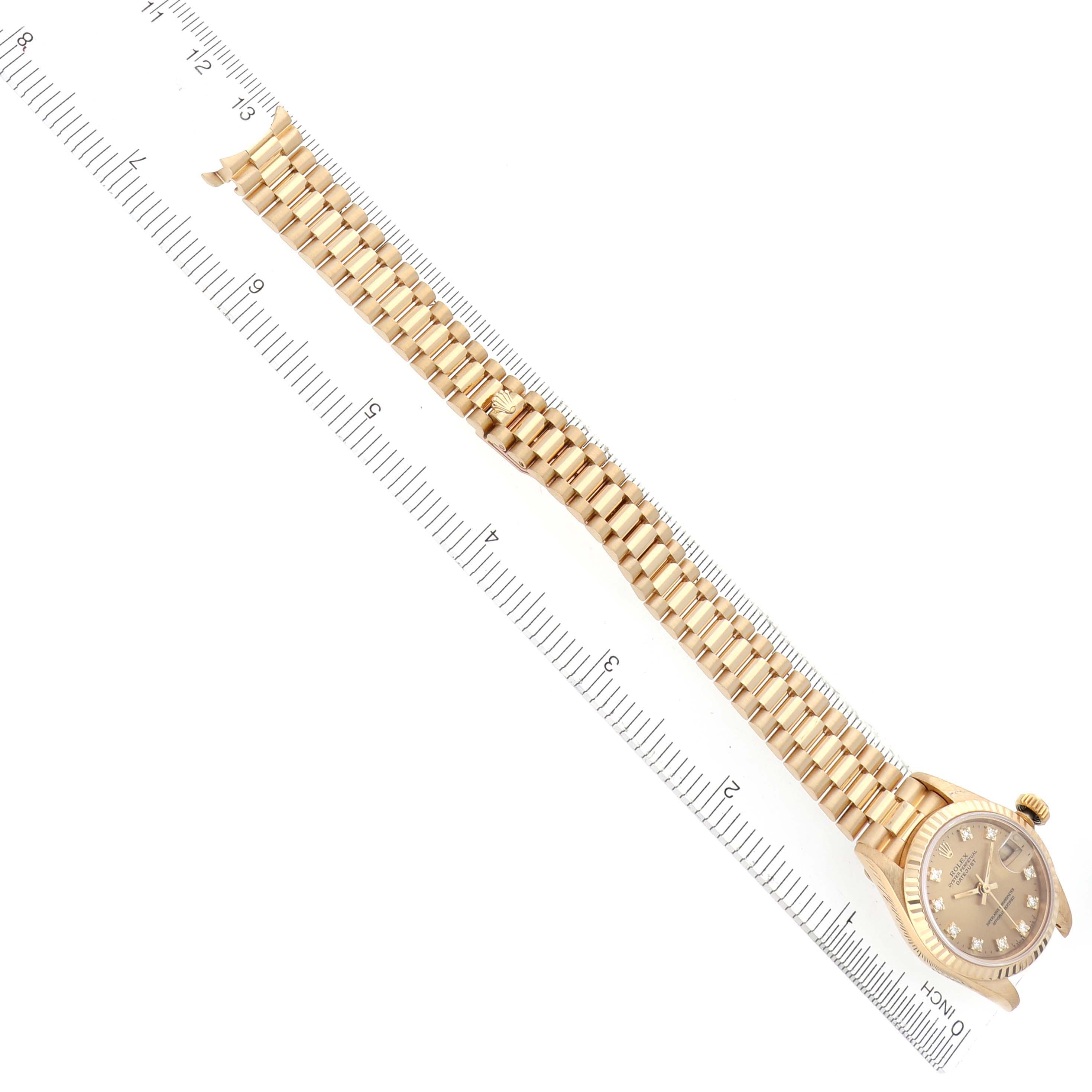 The image shows a Rolex President 69178 Women's Yellow Gold Champagne Dial 69178 Women's Yellow Gold Champagne Dial model watch from an overhead angle, highlighting the bracelet and dial next to a ruler.