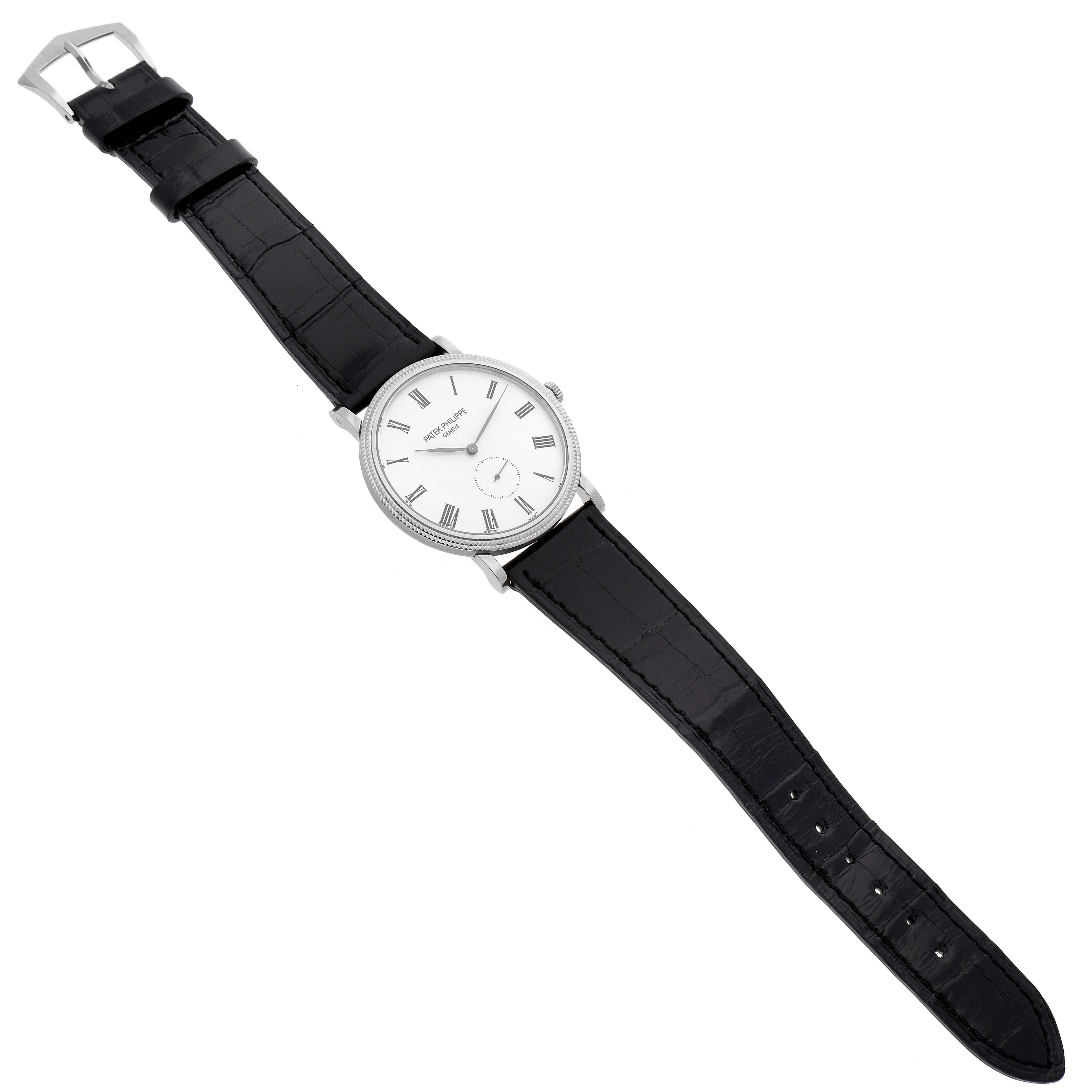 The image shows a Patek Philippe Calatrava 5119G Men's Yellow Gold White Dial 5119G Men's Yellow Gold White Dial watch with a top-down view of the face, black leather strap, buckle, and crown.