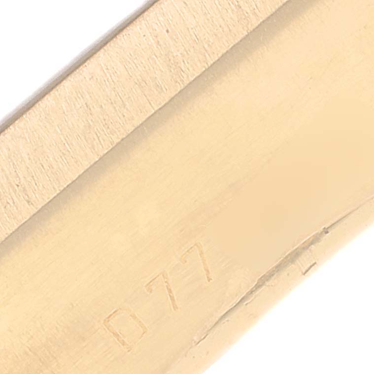The image shows a close-up of a part of the strap or case of the Rolex Cellini 5440/8 Men
s Yellow Gold Champagne Dial 5440/8 Men
s Yellow Gold Champagne Dial watch with a serial number engraved.