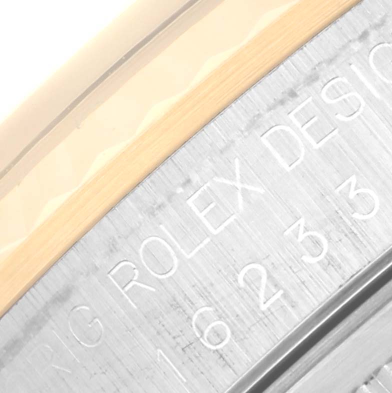 The image shows a close-up angle of the Rolex Datejust 16233 Men's Steel and Gold (two tone) Blue Dial 16233 Men's Steel and Gold (two tone) Blue Dial's stainless steel case with engraved text.