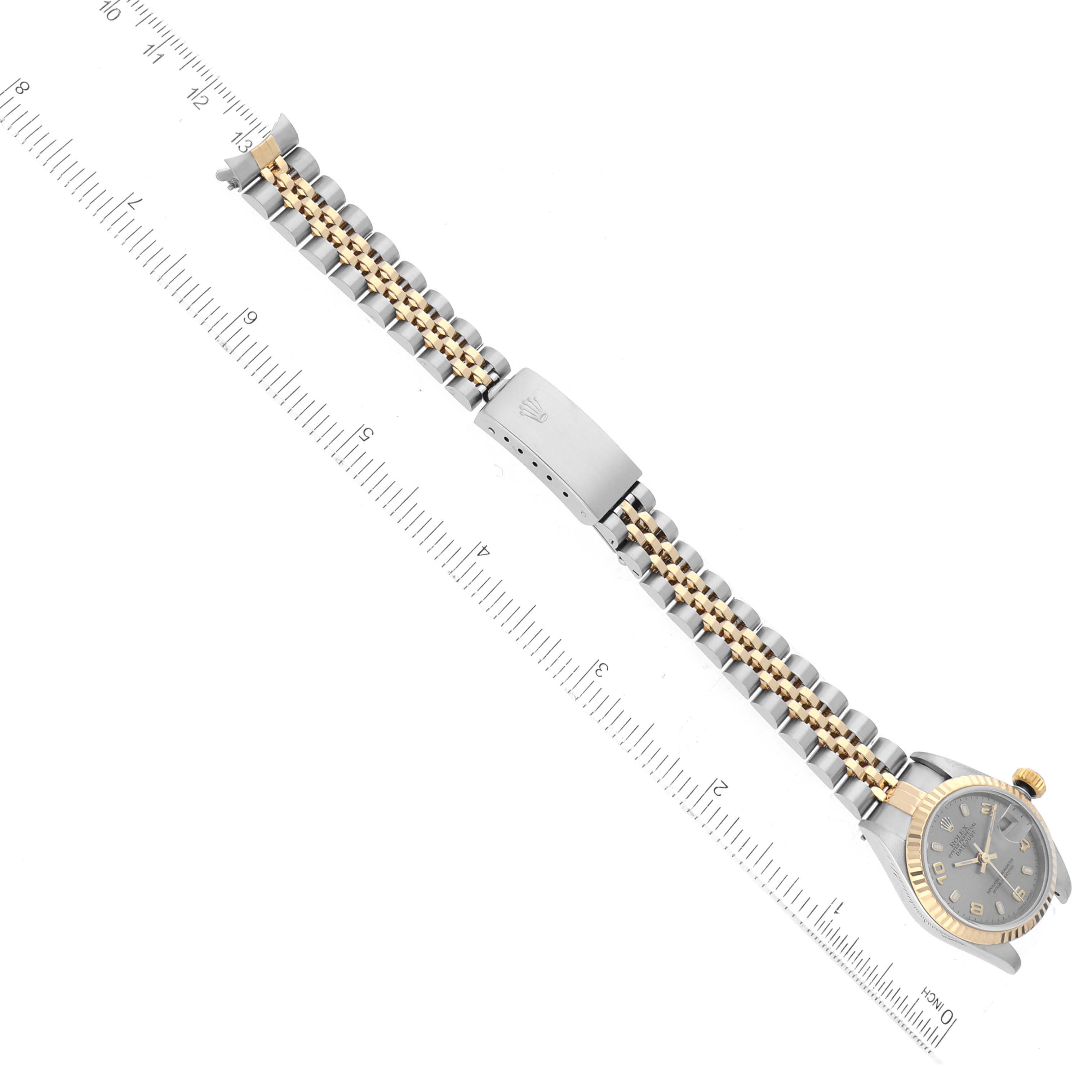 The image shows the full length of a Rolex Datejust 79173 Women's Steel and Gold (two tone) Grey Dial 79173 Women's Steel and Gold (two tone) Grey Dial watch, including the face, clasp, and bracelet, laid flat next to a ruler.