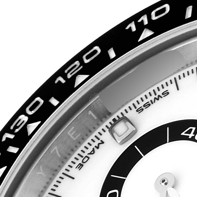The image shows a close-up of the bezel and part of the dial of a Rolex Daytona 116500 Men
s Stainless Steel White Dial 116500 Men
s Stainless Steel White Dial watch, highlighting the tachymeter scale.