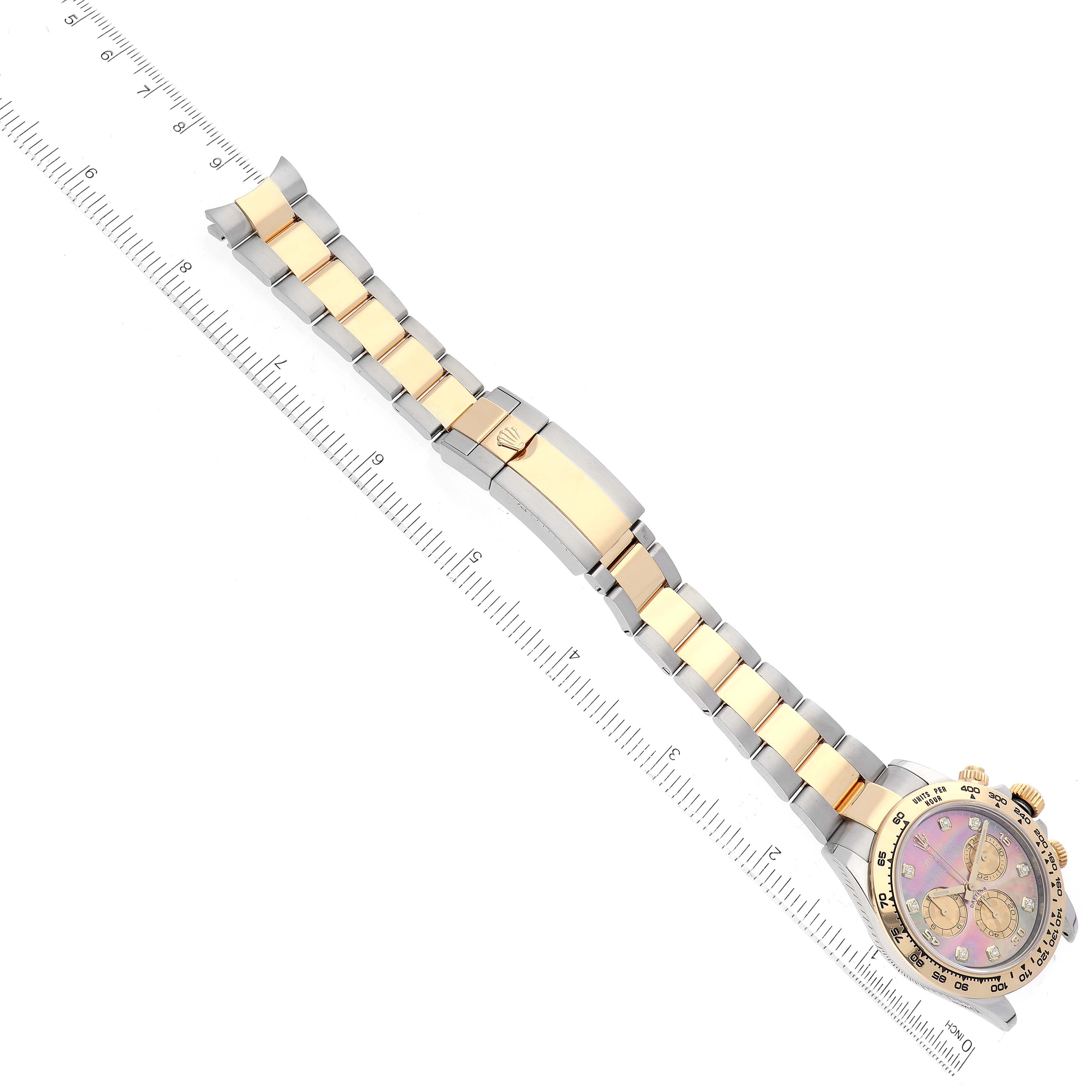 The image shows a Rolex Daytona 116503 Men
s Steel and Gold (two tone) Mother of Pearl Dial 116503 Men
s Steel and Gold (two tone) Mother of Pearl Dial watch laid flat with a ruler, highlighting its strap and clasp.