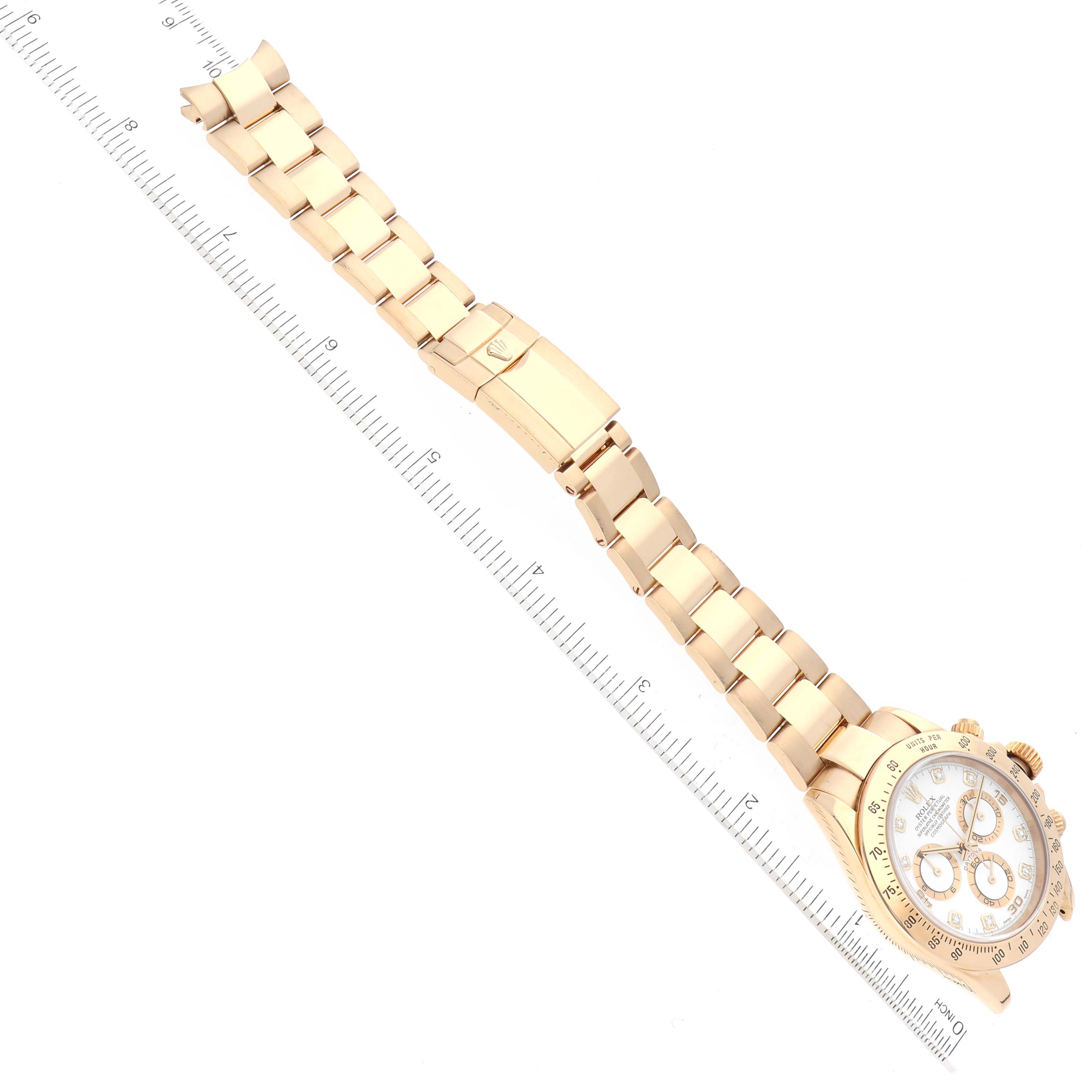 The image shows a Rolex Daytona 116528 Men's Yellow Gold White Dial 116528 Men's Yellow Gold White Dial model watch laid straight with its band fully extended next to a ruler.