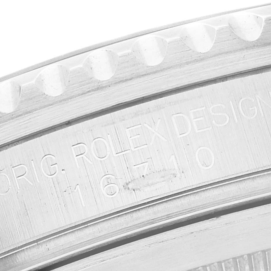 The image shows a close-up of the edge of a Rolex GMT-Master 16710 Men
s Stainless Steel Black Dial 16710 Men
s Stainless Steel Black Dial watch case, highlighting the "ROLEX DESIGN" engraving and model number 16710.