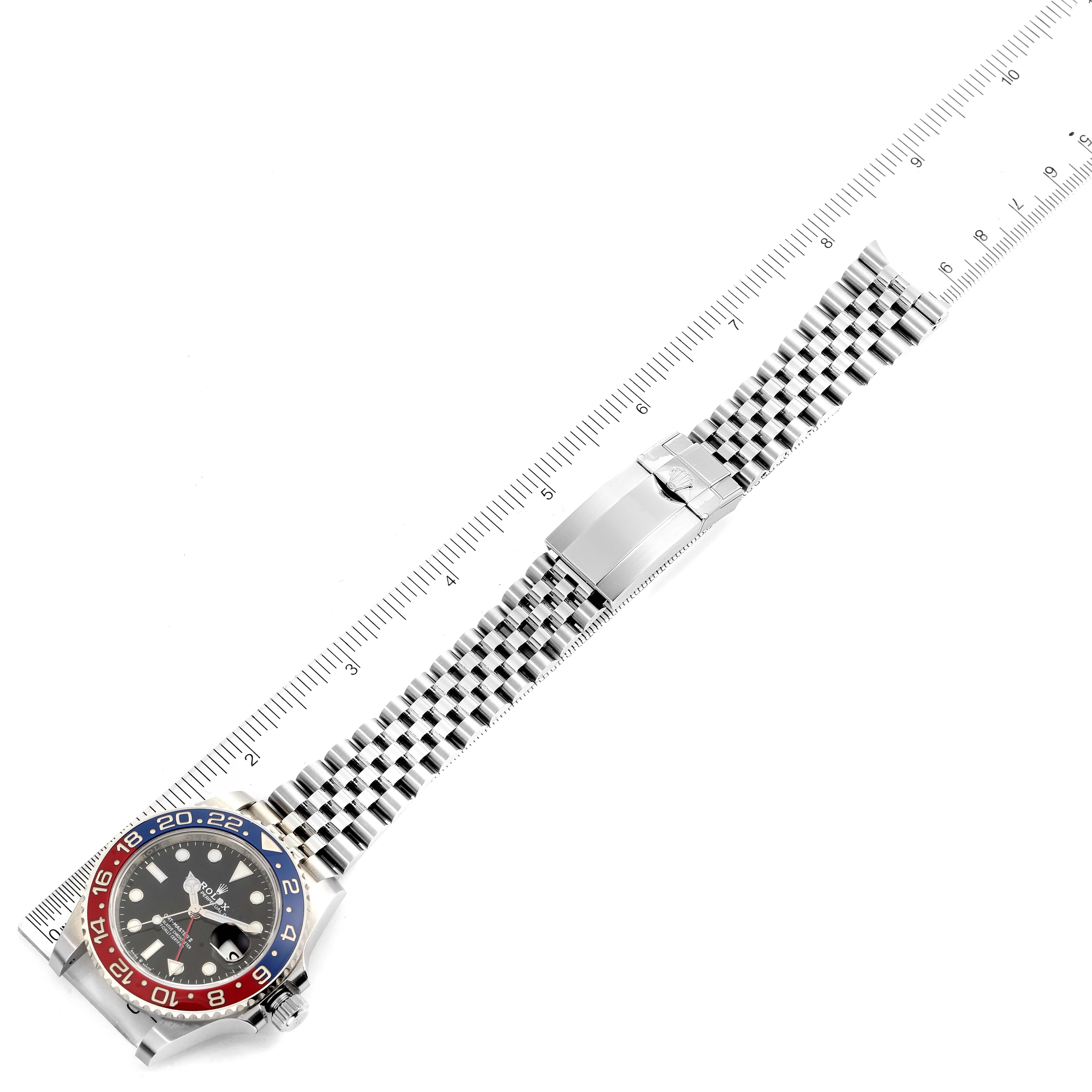 This image shows a Rolex GMT-Master 126710 Men
s Stainless Steel Black Dial 126710 Men
s Stainless Steel Black Dial watch laid flat, with a ruler beside it for scale.