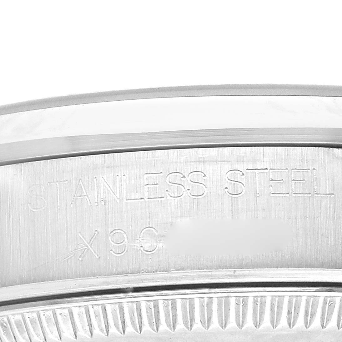 The image shows a close-up view of the mid-size Rolex watch bezel and its engraved "STAINLESS STEEL" detail.