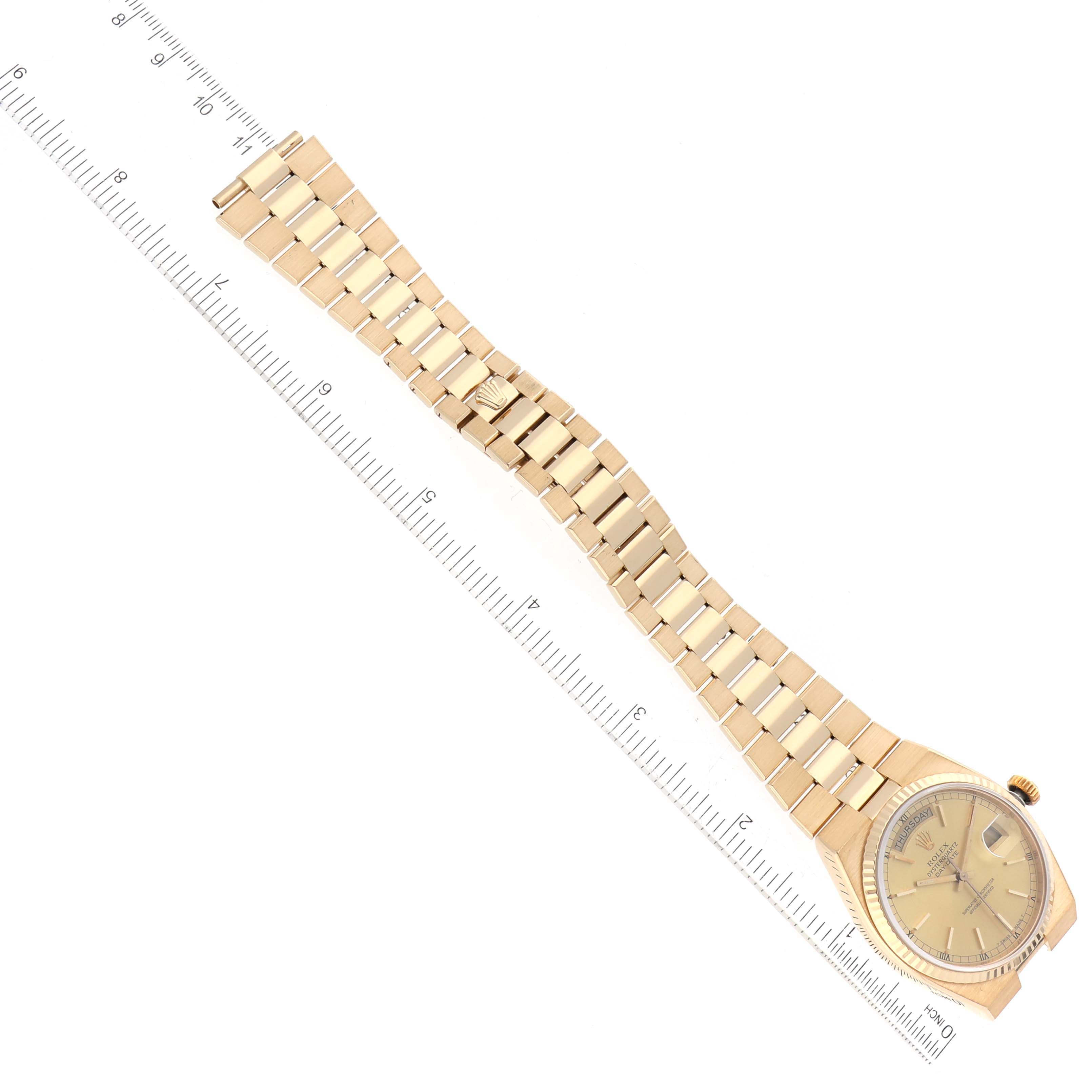 The Rolex Oysterquartz 19018 Men's Yellow Gold Champagne Dial 19018 Men's Yellow Gold Champagne Dial watch is shown from a top-down angle alongside a ruler.