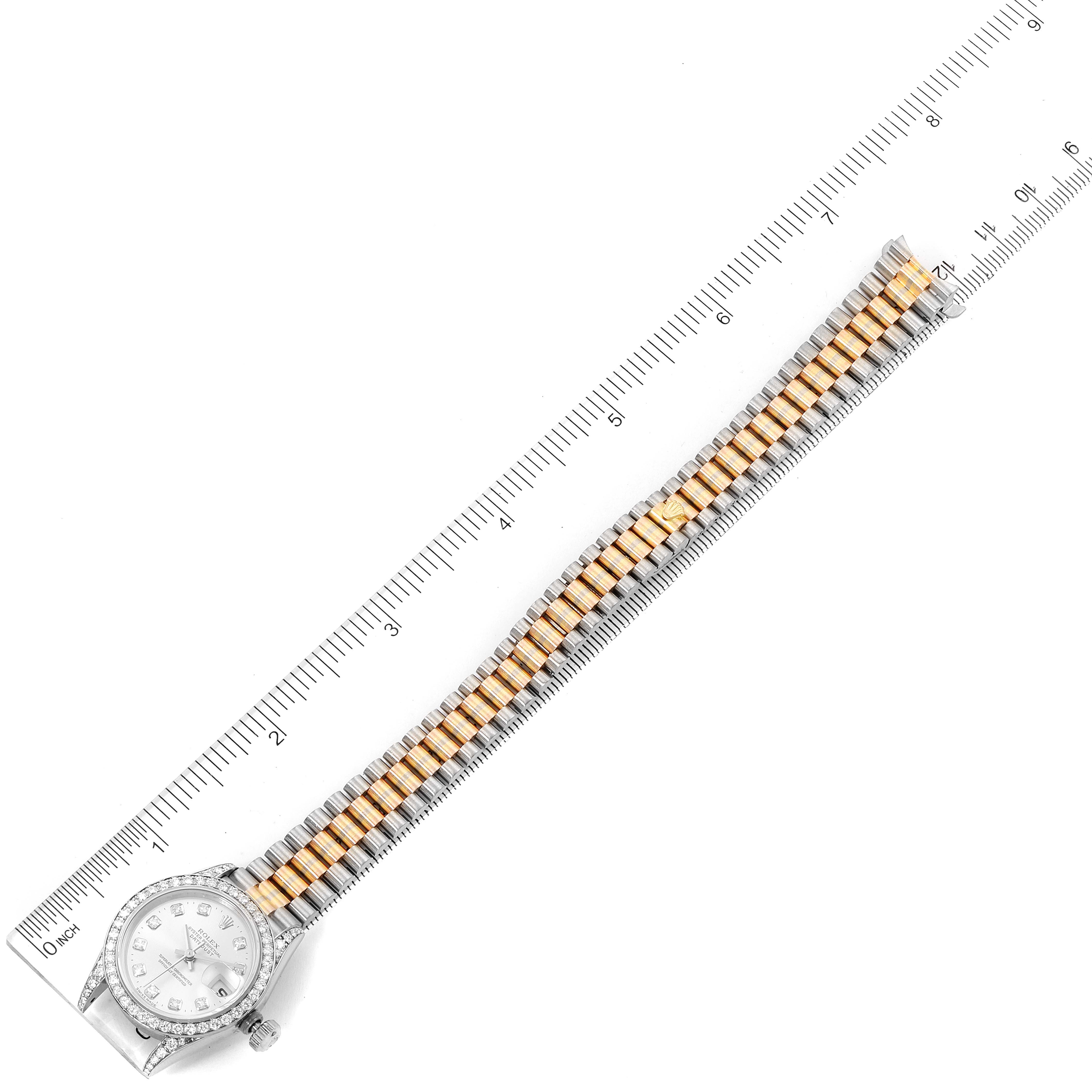 This image shows a top view of a Rolex President 69159 Women
s White Gold Silver Dial 69159 Women
s White Gold Silver Dial watch, displaying the full watch band and case alongside a ruler for scale.
