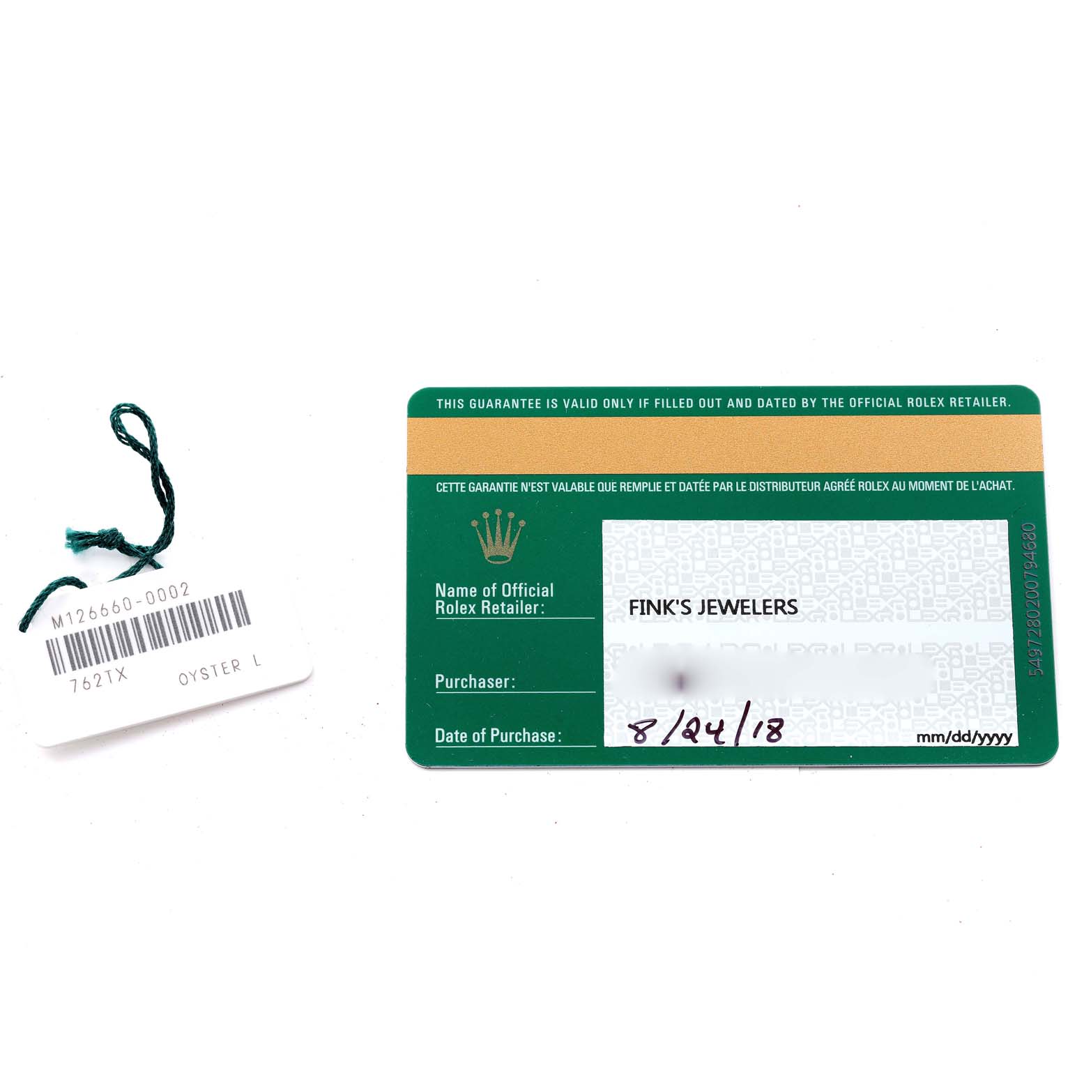 The image shows a green warranty card and a white tag with numbers and a green string, both accessories for a Rolex Sea-Dweller 126660 Men
s Stainless Steel Blue Dial 126660 Men
s Stainless Steel Blue Dial watch.