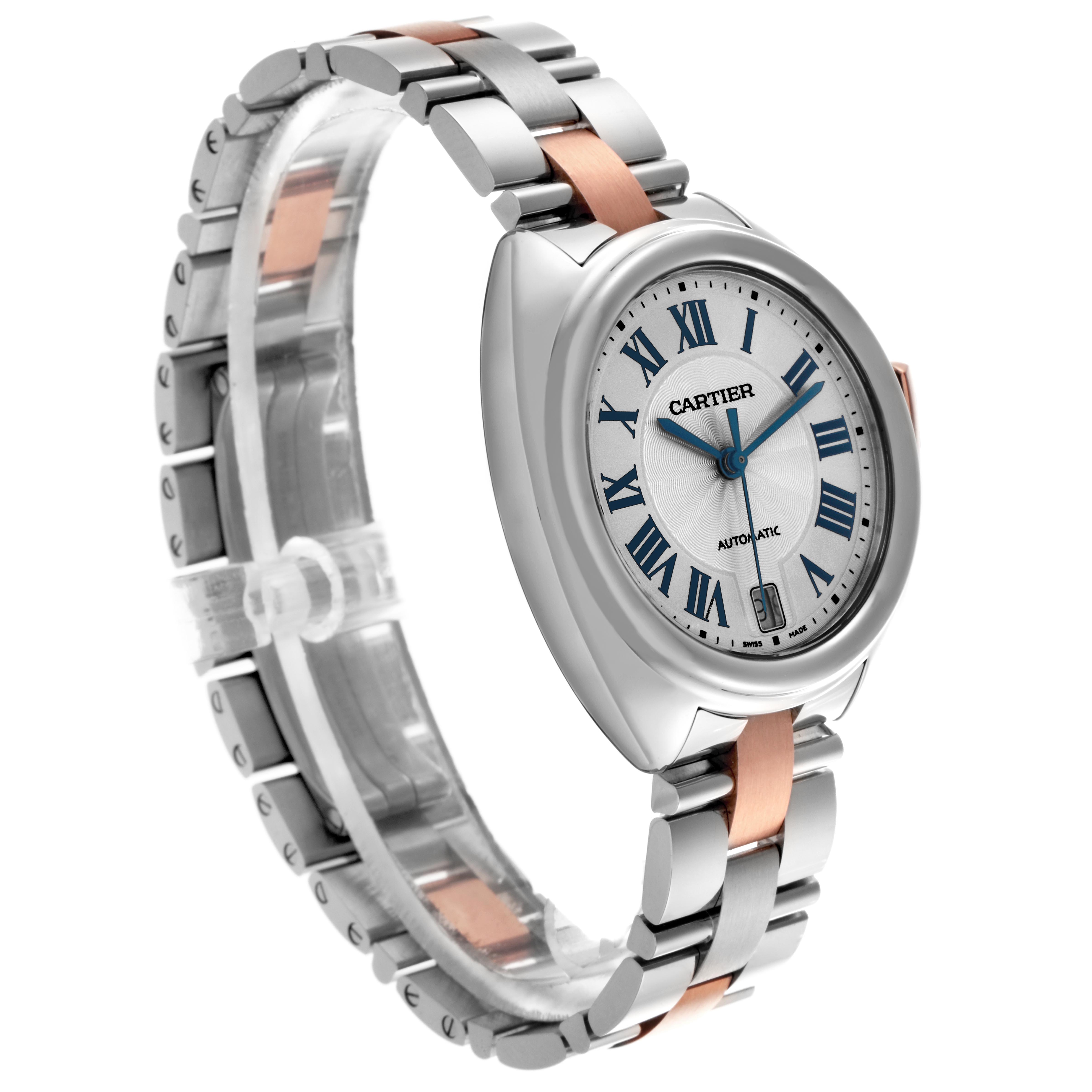 The Cartier Clé watch is shown at a three-quarter angle, displaying its round face, Roman numerals, and metal bracelet.