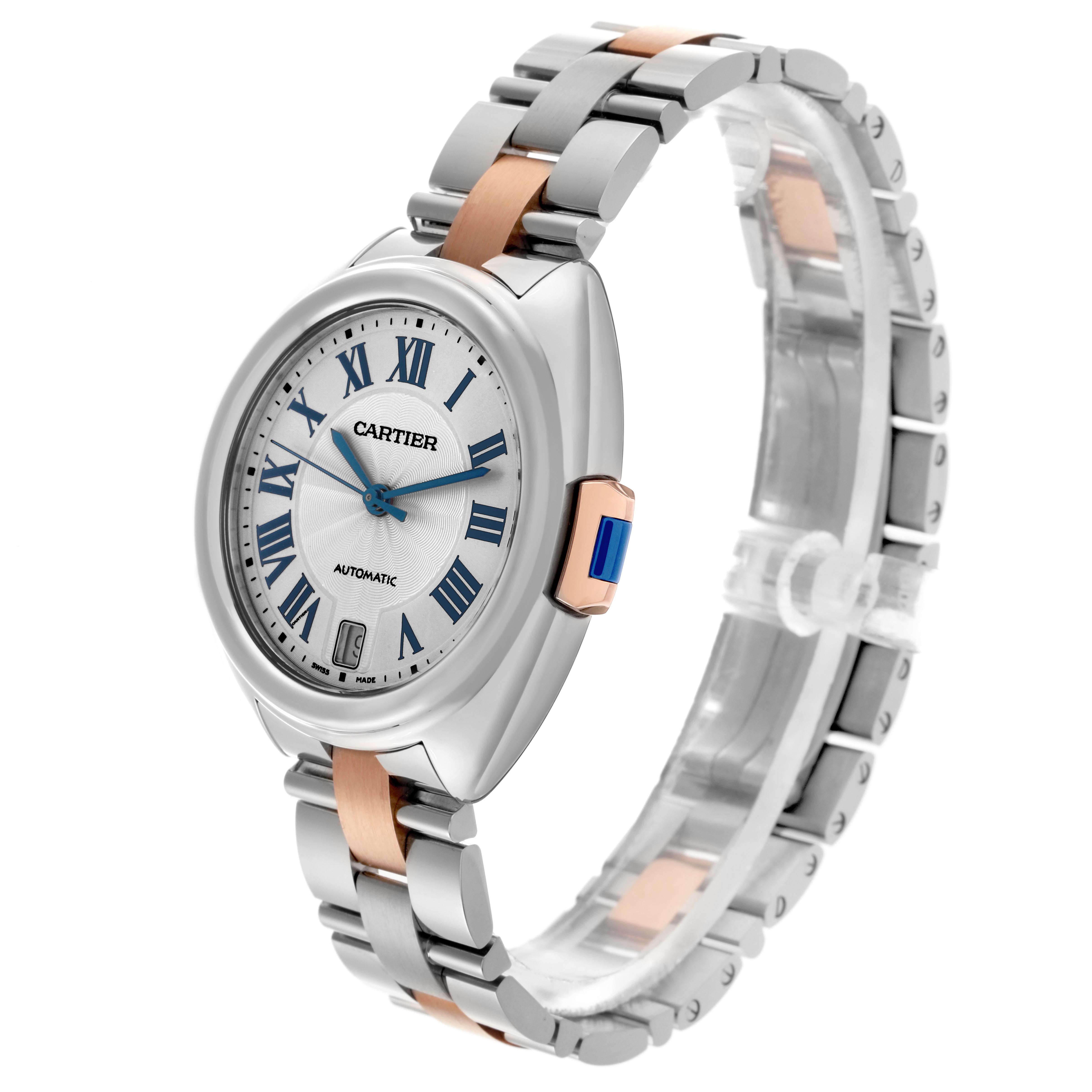 The Cartier Clé watch is shown at a three-quarter angle, displaying the face, Roman numerals, and metal bracelet.