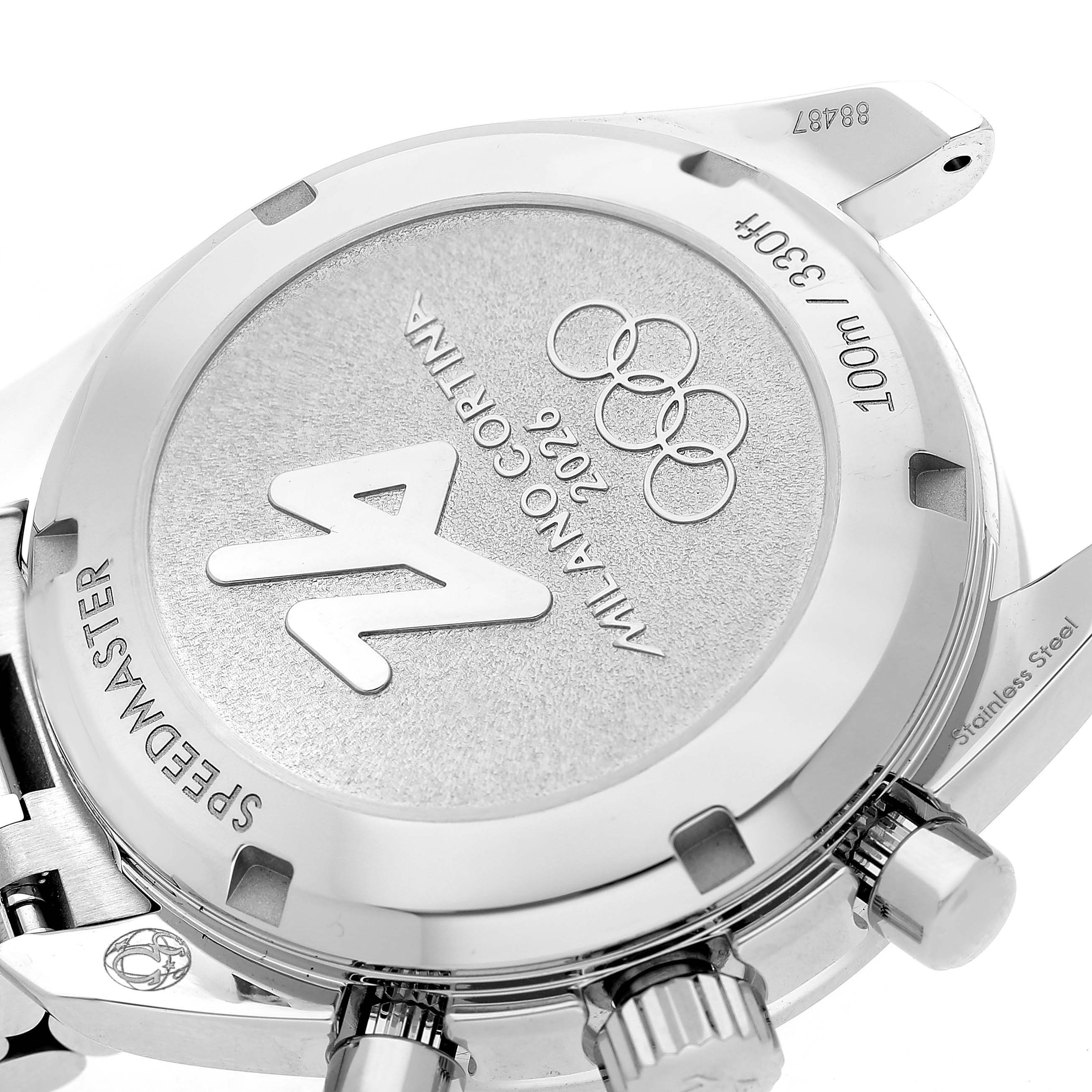 The image shows the case back of an Omega Speedmaster 324.30.38.40.04.001 Men's Stainless Steel White Dial watch from an angled view, highlighting the Milano Cortina 2026 engraving and Olympic rings.