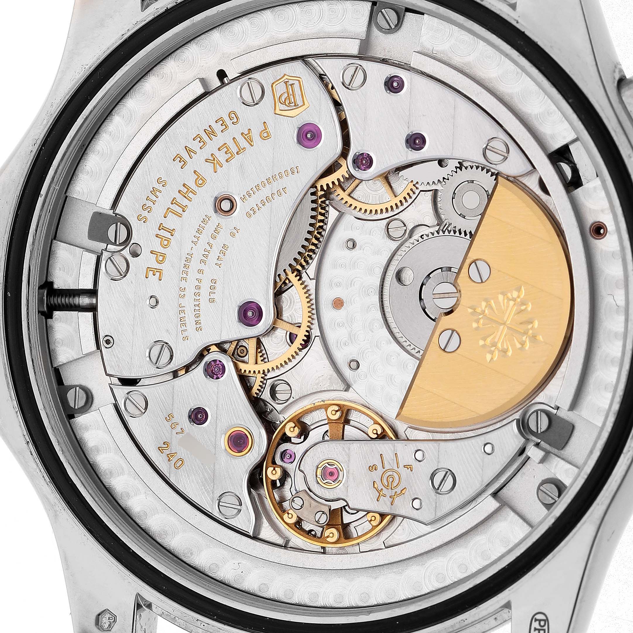 The image shows the movement from the back of a Patek Philippe Complications 5130/1G-010 Men's White Gold Black Dial watch, highlighting gears, jewels, and the rotor.